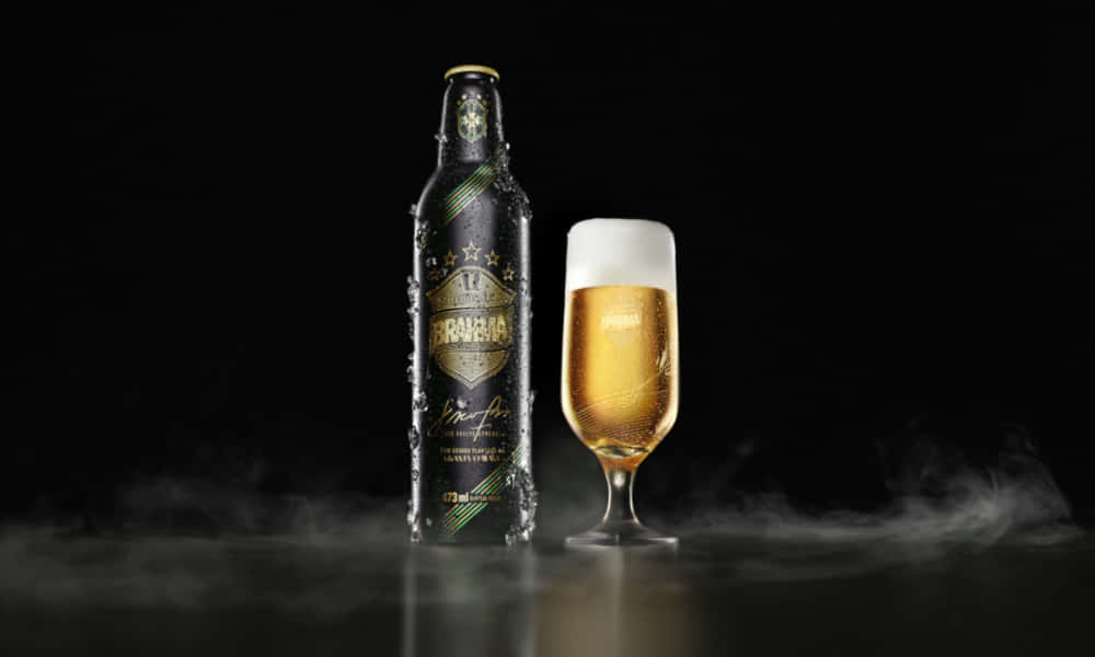 冰凍的Brahma啤酒瓶和裝有金色液體和白色泡沫的玻璃杯，黑暗表面上有薄霧。