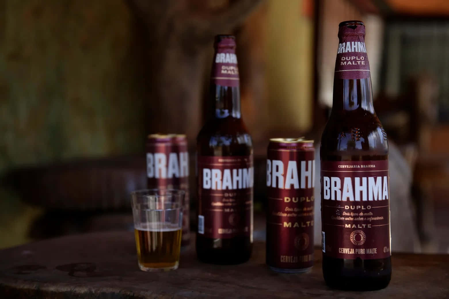 木桌上的 Brahma 啤酒瓶、罐和玻璃杯
