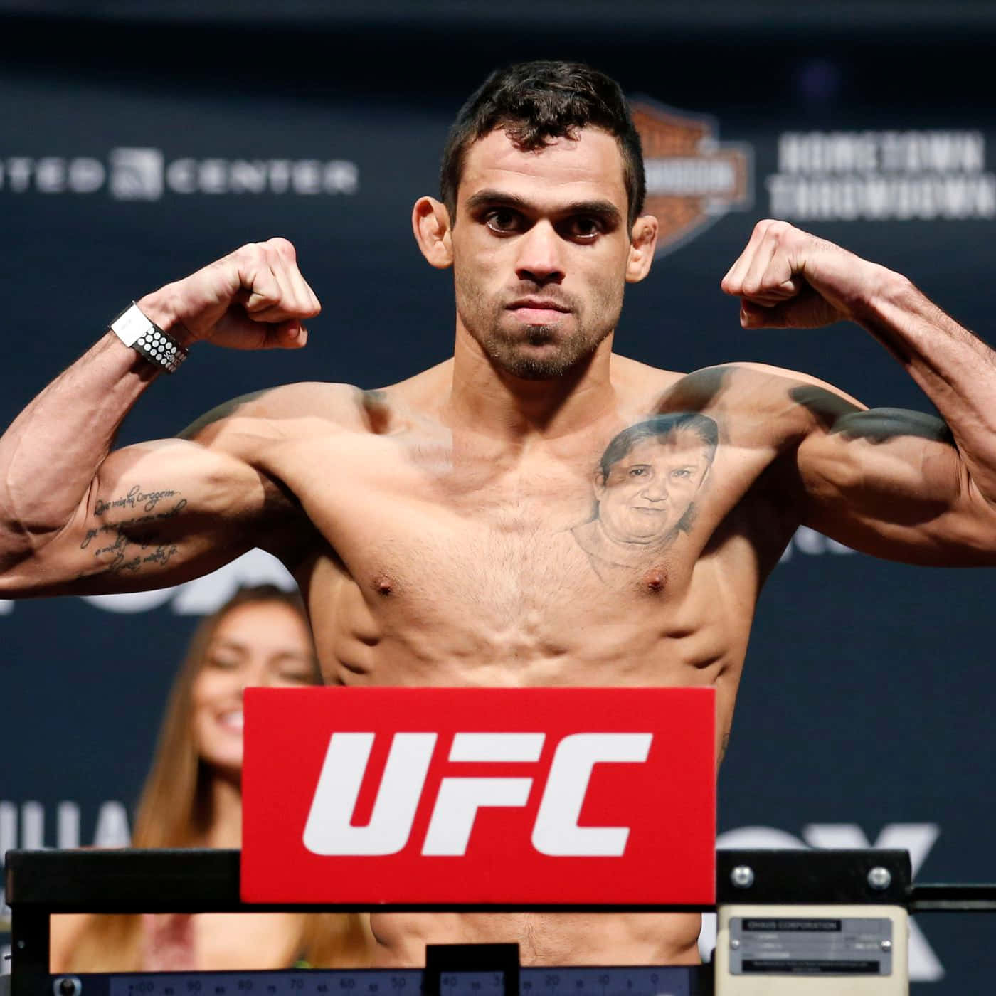 巴西綜合格鬥選手雷南·巴羅半身照展臂 壁紙 — 一位肌肉發達的UFC拳手在稱重時彎曲手臂，展現紋身胸膛和專注眼神。