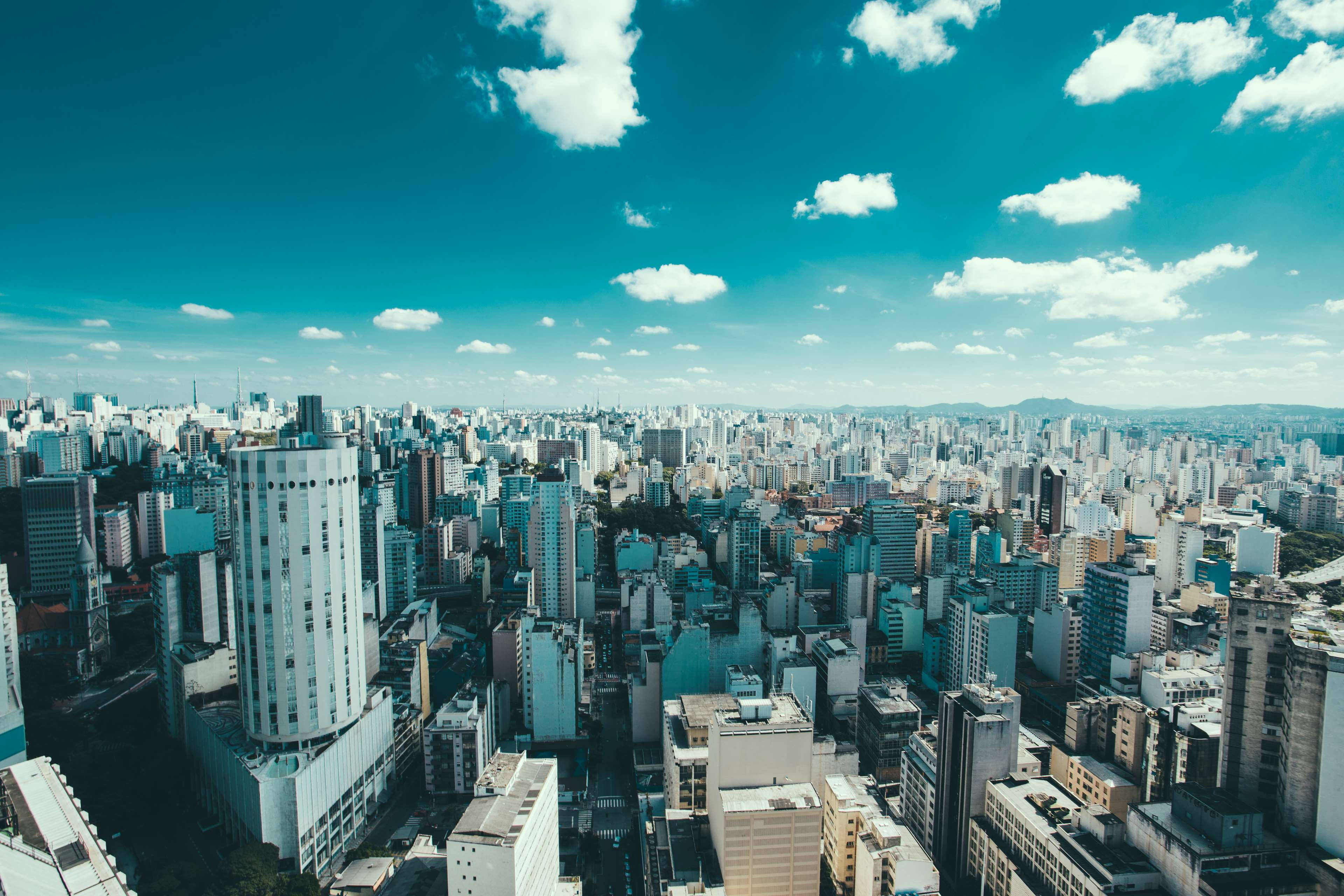 巴西聖保羅濾鏡城市風景 壁紙 — 喺充滿活力嘅藍天白雲下，俯瞰廣闊嘅現代城市景觀嘅航拍相。