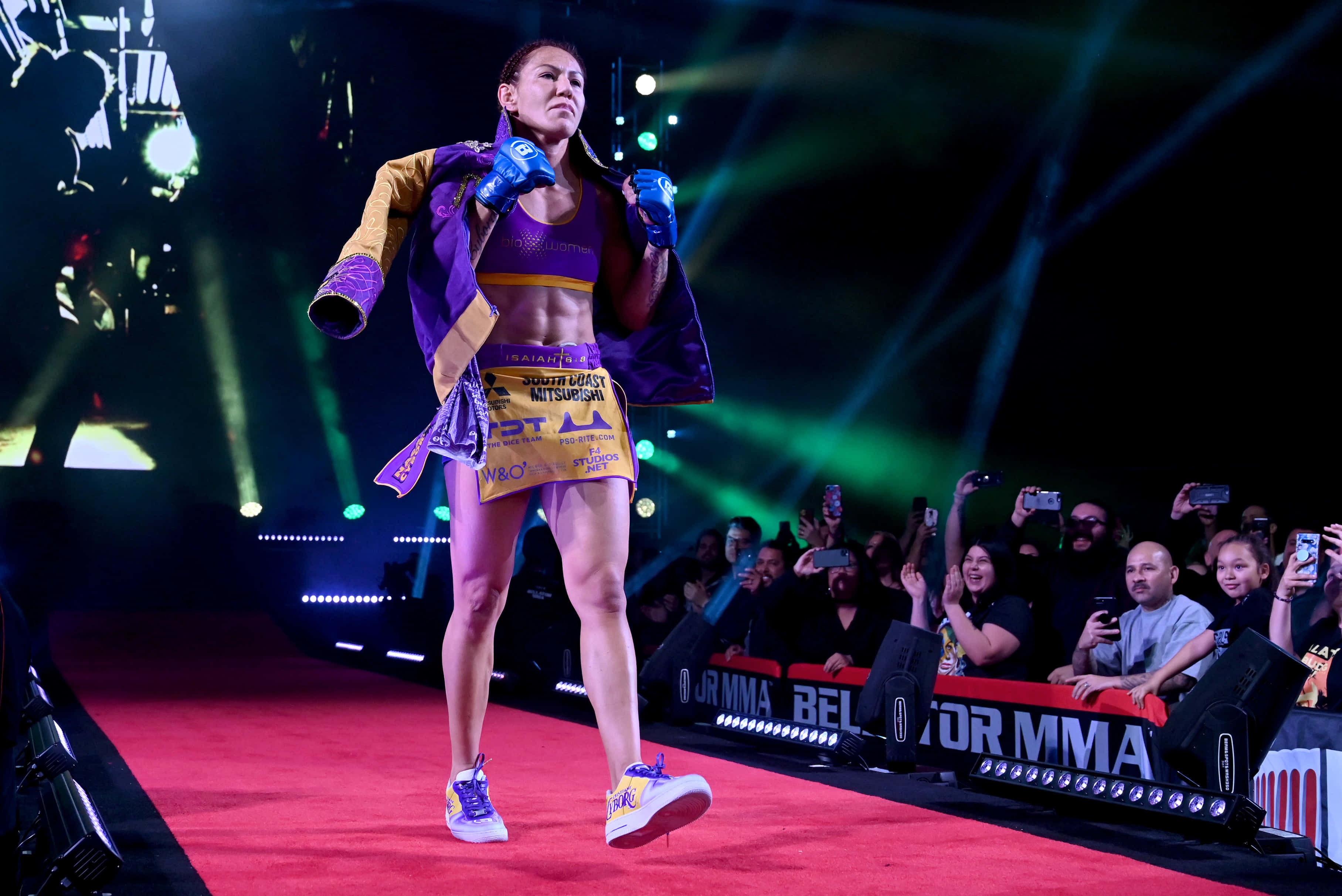 巴西裔美國MMA選手Cris Cyborg 2020 The Forum賽場入場照 壁紙 — 一位女性MMA拳手在充滿活力的綠色舞台燈光下自信地走過紅地毯，身後是熱情的群眾。