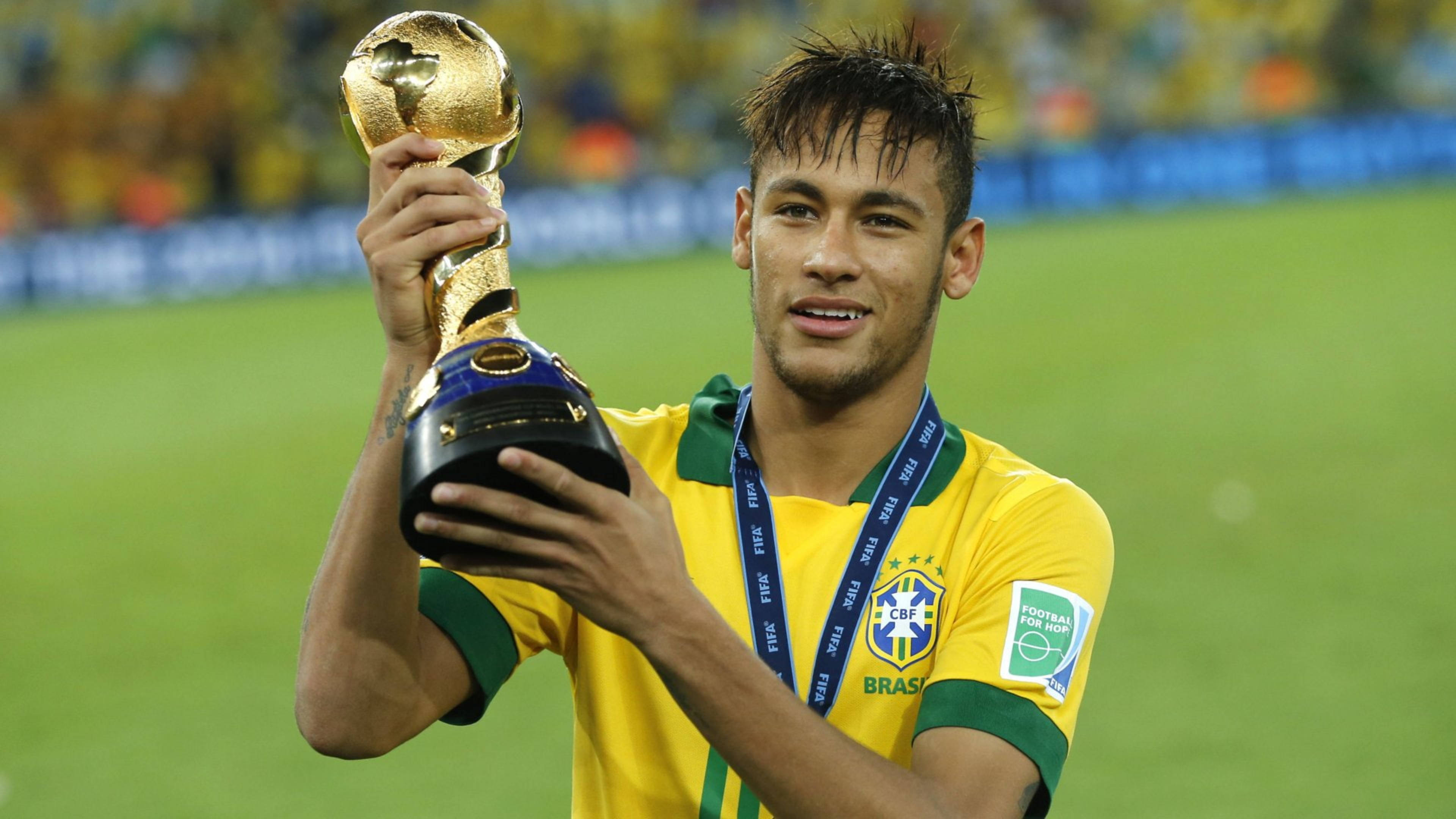 Football Players 桌布 壁紙 — 巴西足球員尼馬在充滿活力的綠色球場上自豪地微笑，手持閃閃發光的世界盃獎盃。