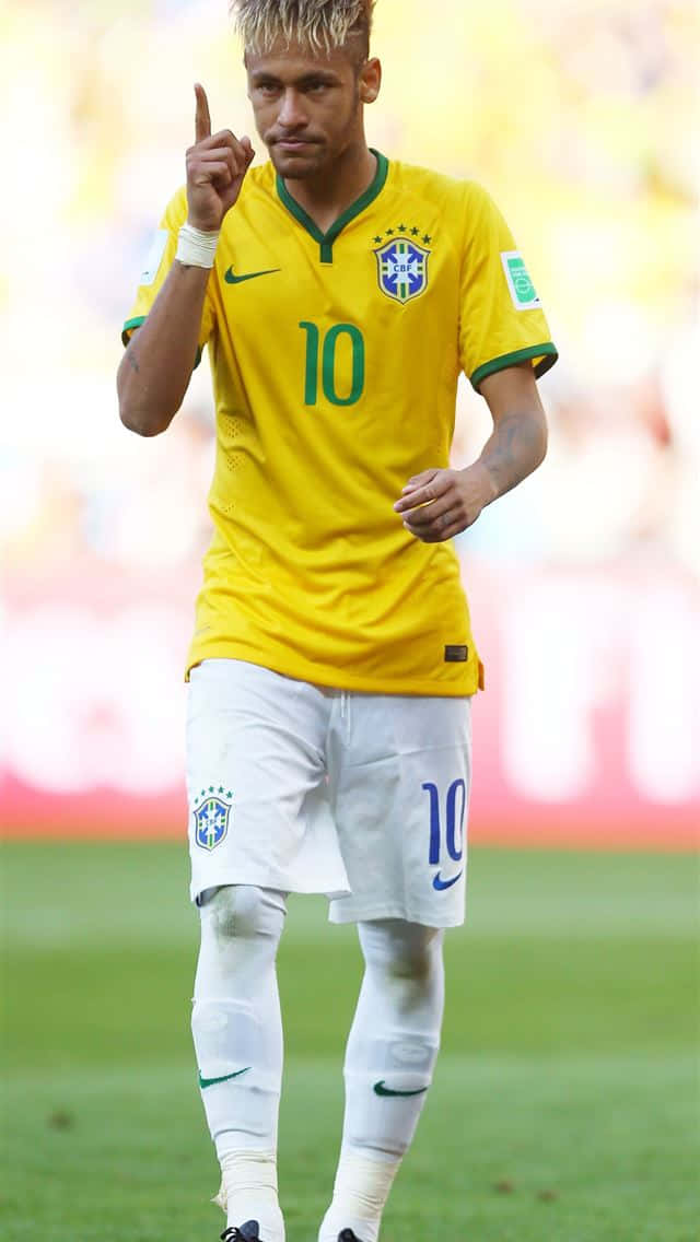 Neymar 桌布 壁紙 — 巴西足球員尼馬身穿黃色10號球衣，在模糊球場背景的綠色草地上向上指。