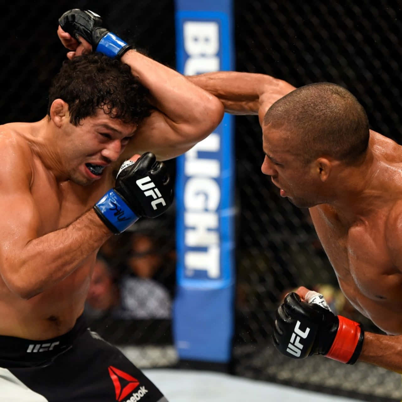 巴西選手埃德森·巴博薩對戰吉爾伯特·梅倫德斯，UFC Fight Night 壁紙 — 兩名MMA拳手在激烈的籠鬥中交鋒，其中一人使出強力頭踢，另一人則痛苦地扭曲表情。