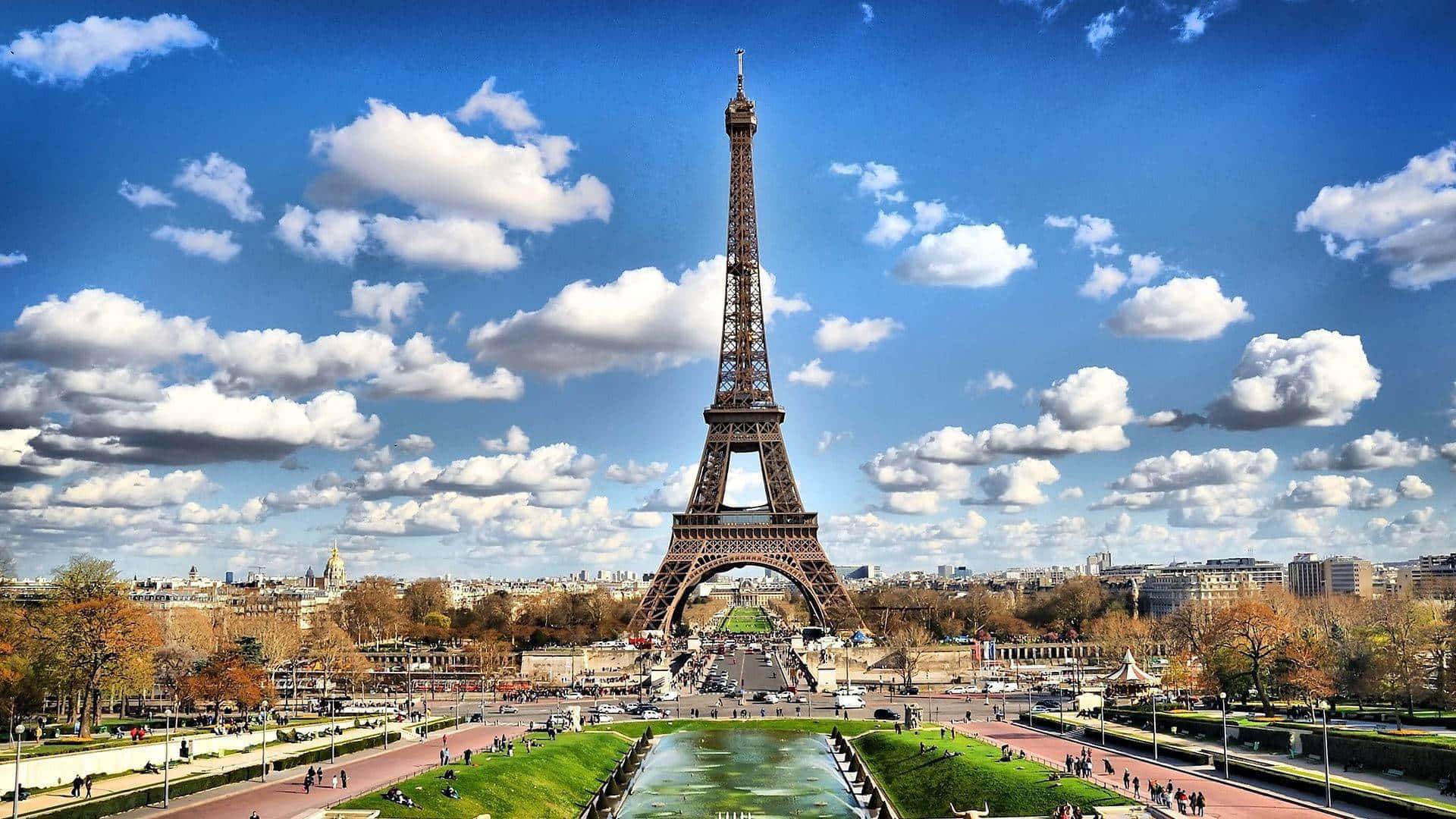 french 桌布 壁紙 — 巴黎的艾菲爾鐵塔在充滿活力的藍天中高聳，點綴著蓬鬆的白雲。