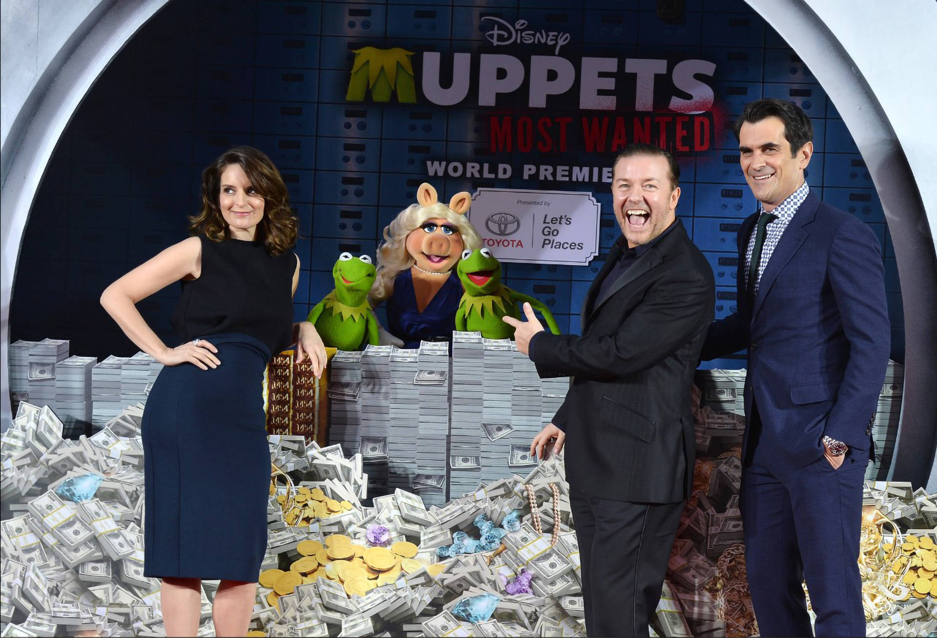 名人與 Muppet 在電影首映禮上站在一堆錢上。