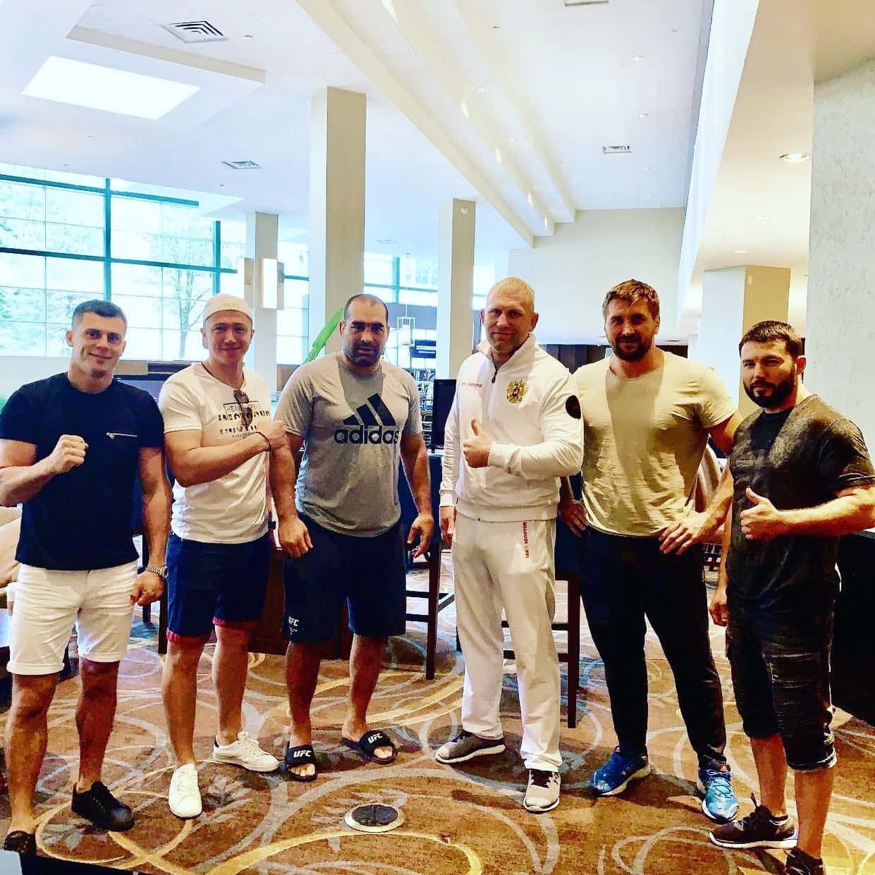 六名男性拳手在酒店大堂穿著運動服一起擺姿勢。