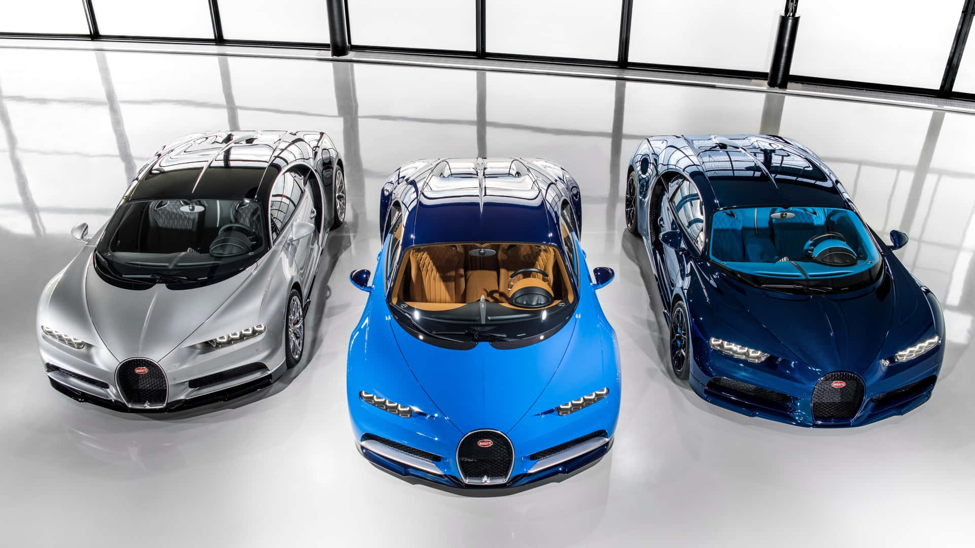 三輛Bugatti超級跑車在明亮簡約的攝影棚中展示，地板具有反光效果。
