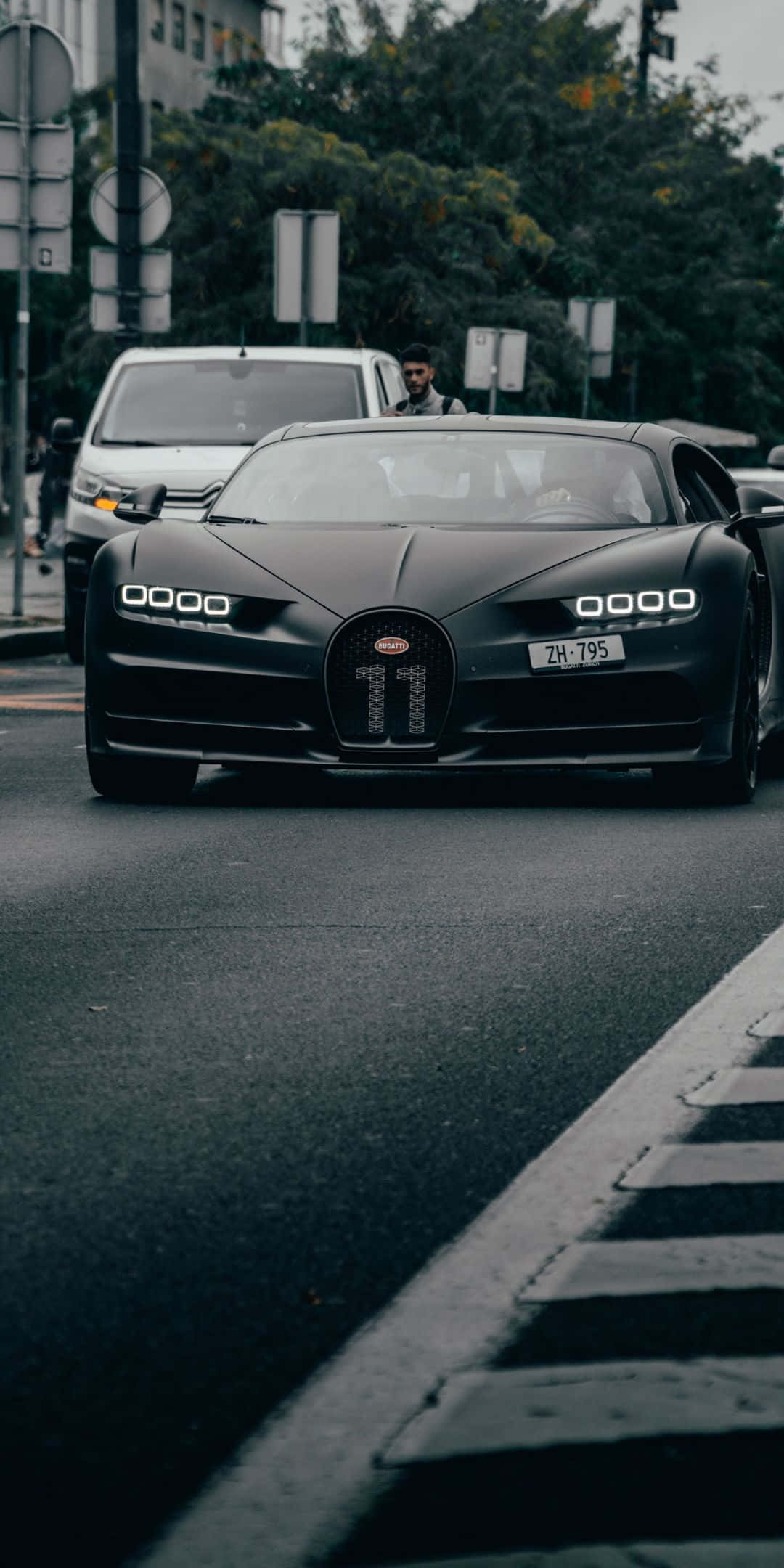 布加迪Chiron磨砂黑車身像素3背景 壁紙 — 一輛霧面黑色的Bugatti Chiron，格柵上有11號，在陰天的主導著城市街道。