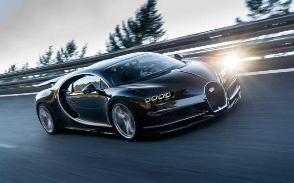 日落時分，黑色Bugatti Chiron在道路上奔馳，背景有樹木。