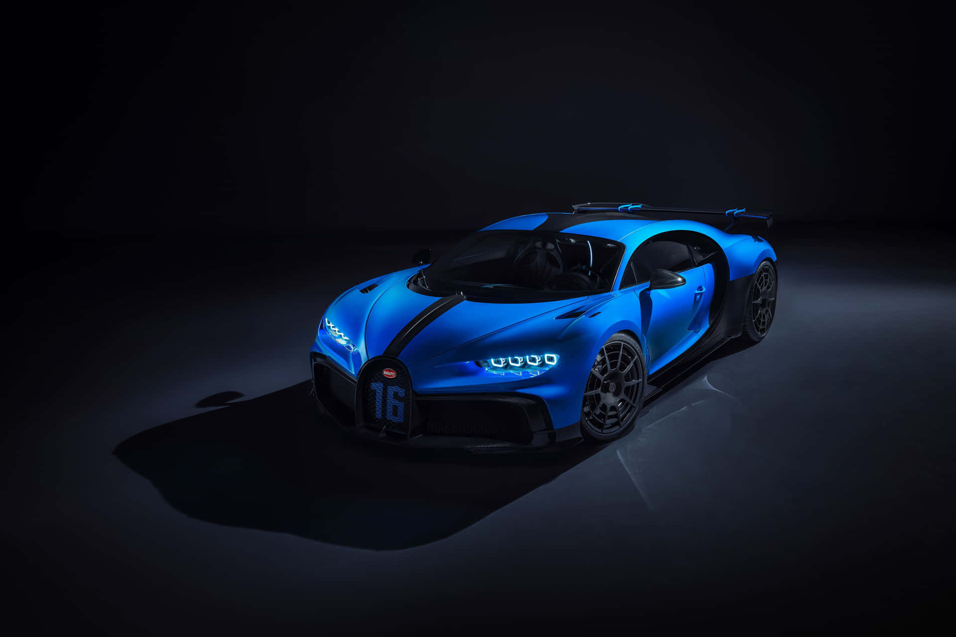 一輛藍色Bugatti跑車在黑暗的工作室環境中被照亮。
