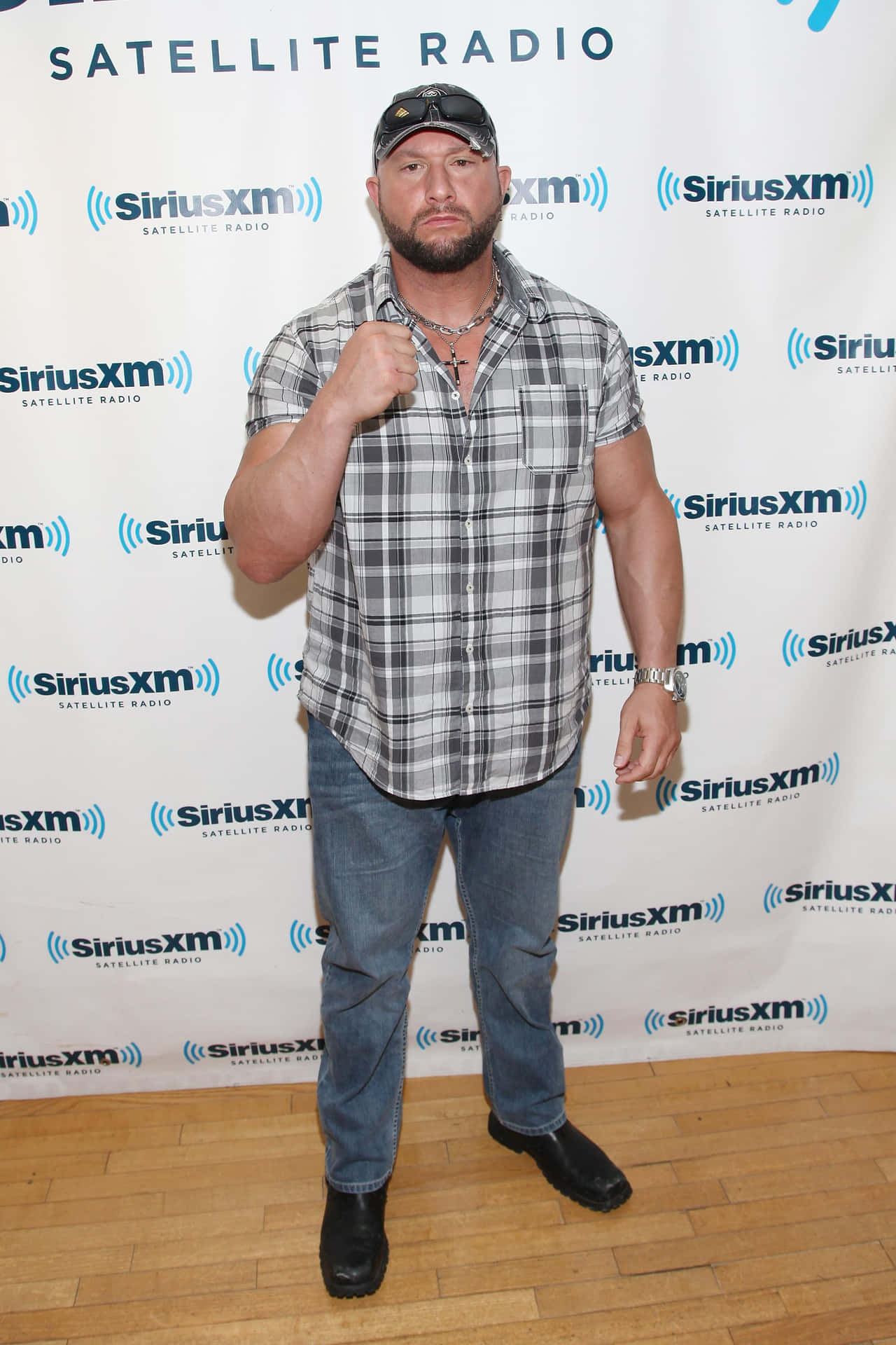 男人穿著格仔恤衫和牛仔褲在SiriusXM活動中舉起拳頭擺姿勢。