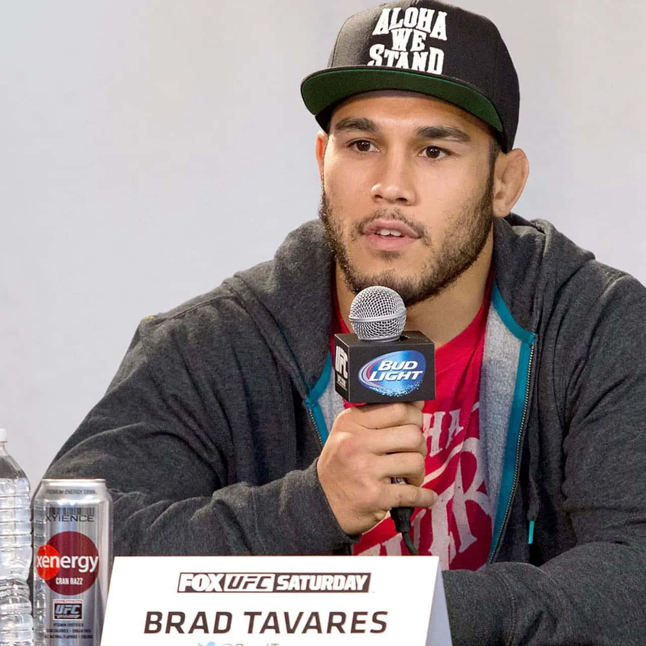 布拉德·塔瓦雷斯手持麥克風 壁紙 — Brad Tavares 在UFC記者會上戴著帽子和連帽衫對著咪高峰講話。
