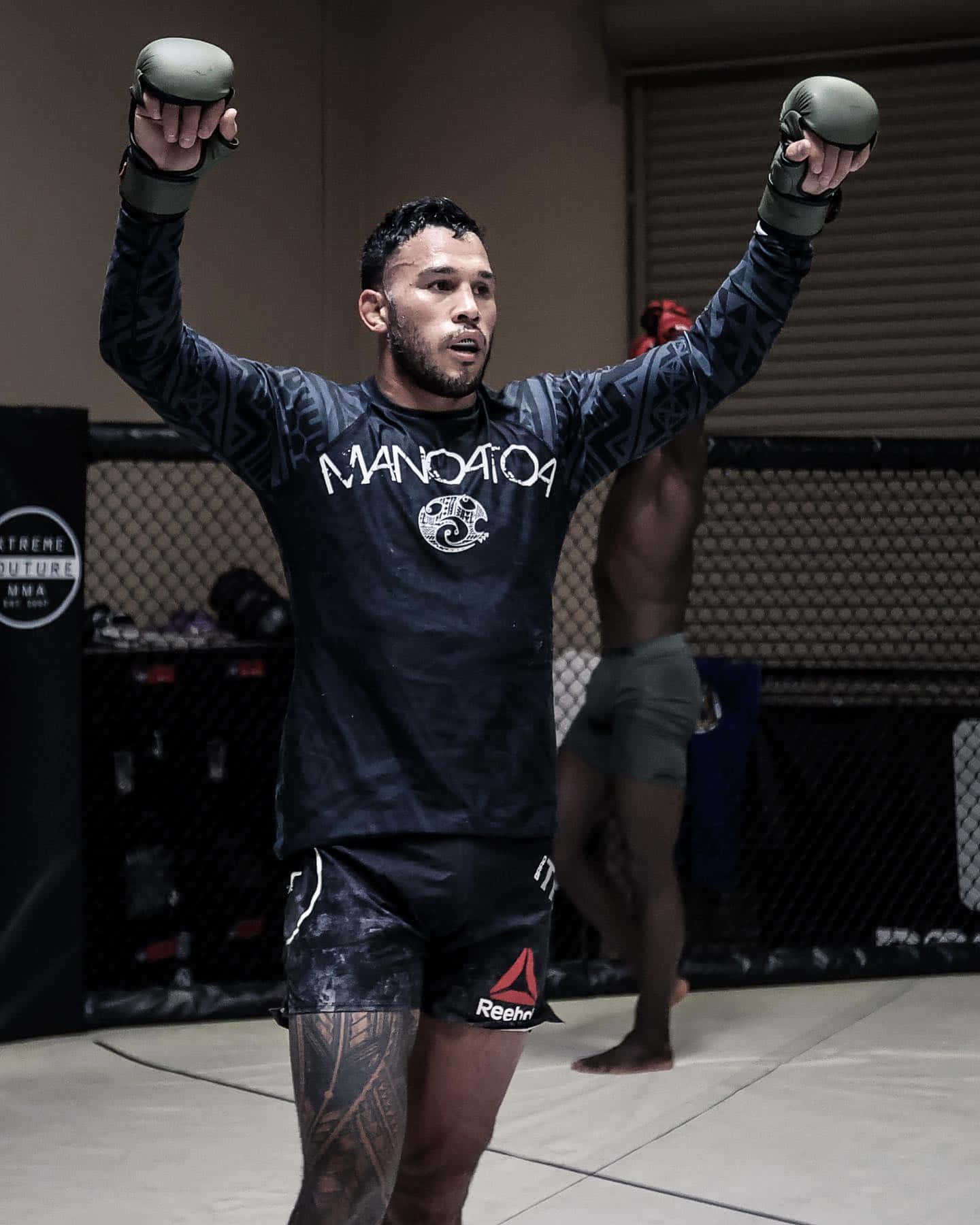 MMA拳手在訓練籠中舉起拳頭慶祝勝利。