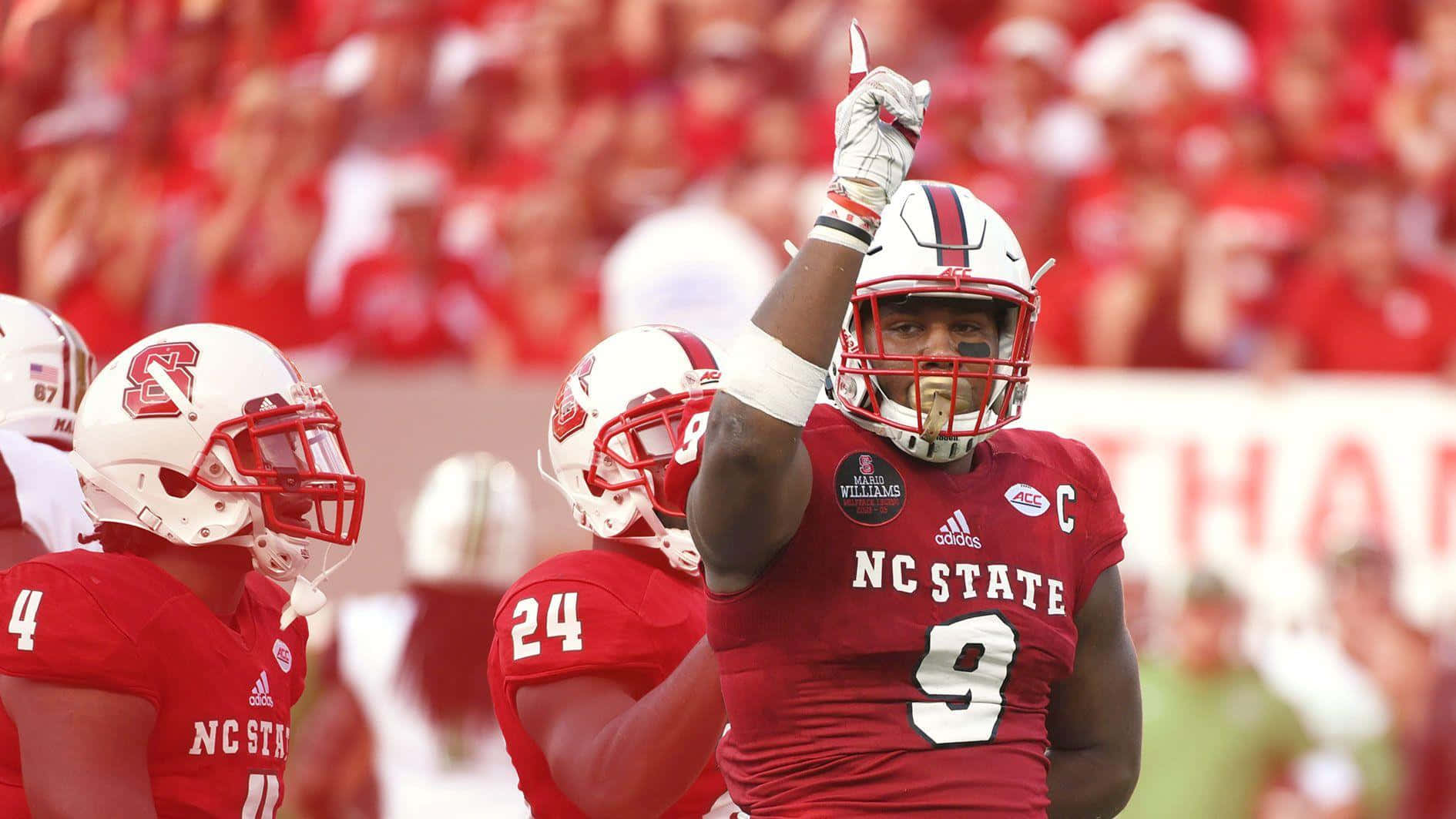 NC State 足球運動員 9 號在比賽中高舉拳頭慶祝勝利。