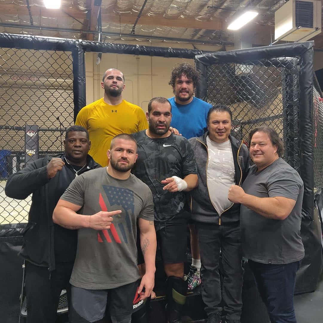 一群MMA拳手在訓練設施的籠內擺姿勢。