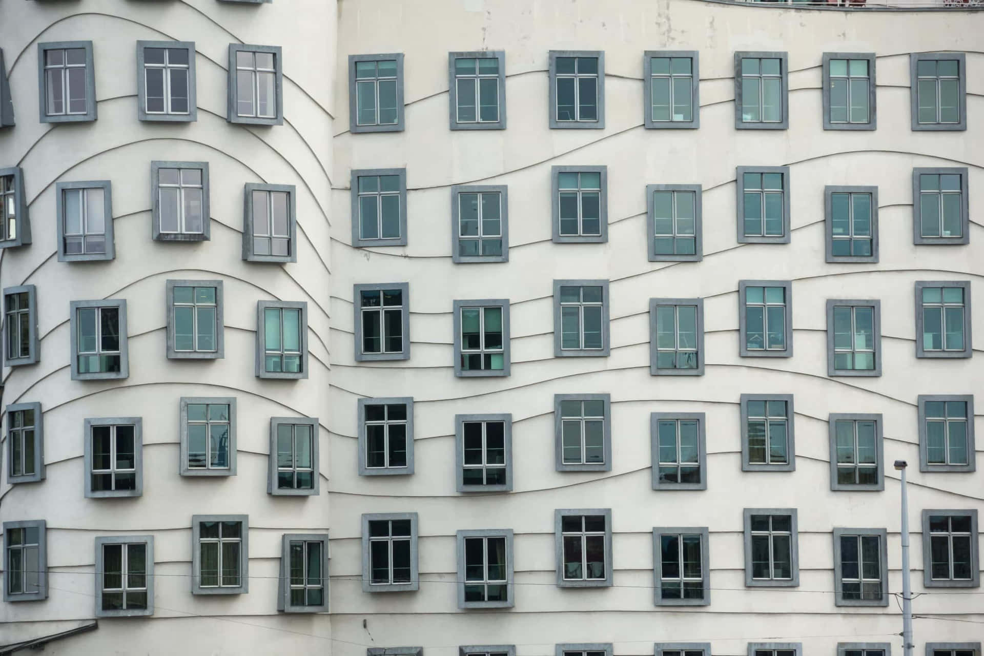 波浪形白色建築，灰色窗戶呈網格圖案。