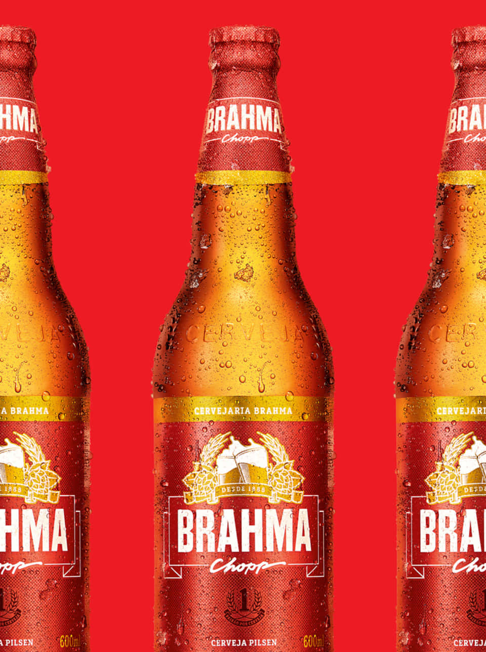 三瓶冰凍的Brahma啤酒瓶，紅色背景上有冷凝水珠。