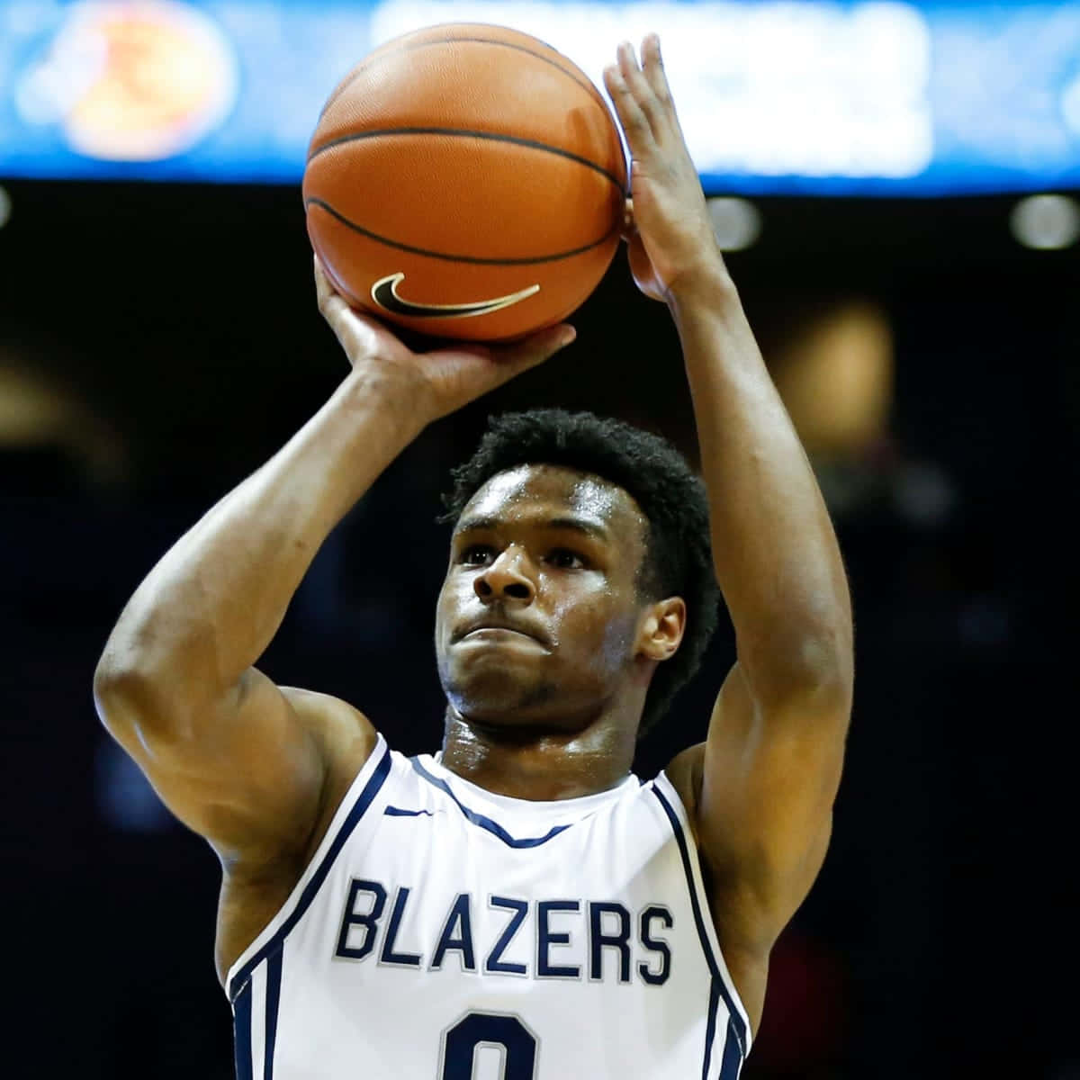 身穿 Blazers 球衣的籃球運動員在場館中投籃。