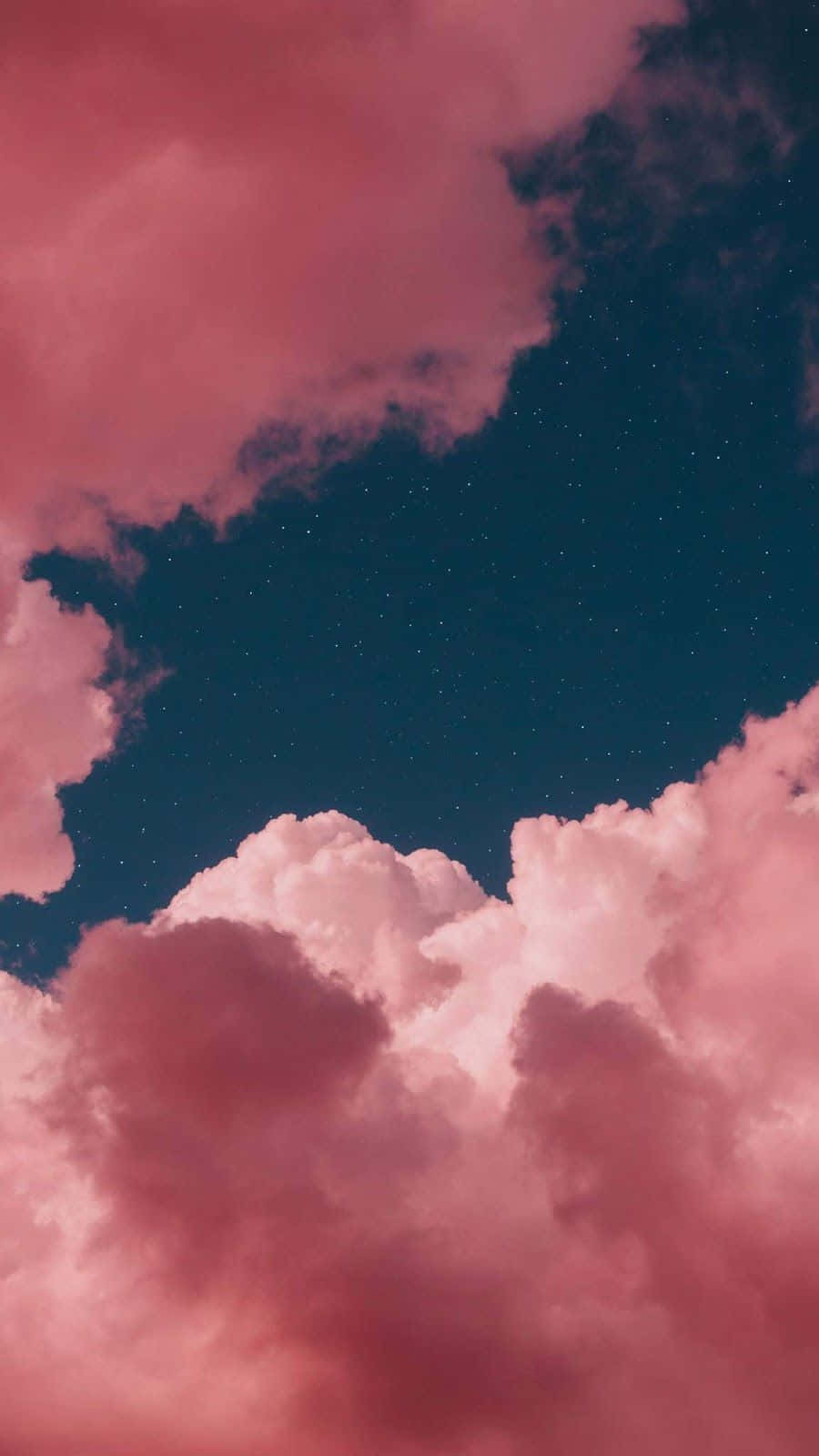 布滿翻滾雲層的陰沉天空 壁紙 — 粉紅色的雲朵在繁星點點的深藍色夜空飄移，營造夢幻的天體場景。
