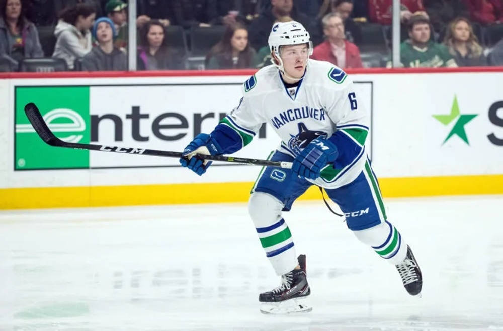 布羅克·布瑟對戰新澤西魔鬼隊 壁紙 — 一名溫哥華加人隊（Vancouver Canucks）冰球運動員身穿白色、藍色和綠色球衣，在比賽中持球桿在冰上激烈滑行。