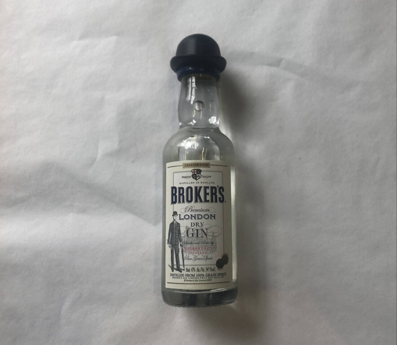 一小瓶 Broker's 氈酒放在白色布料背景上。
