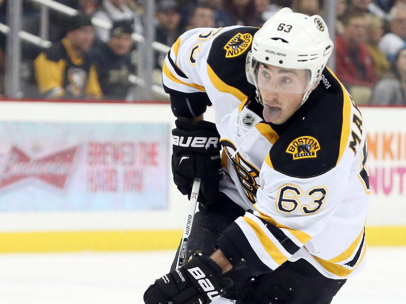布萊德·馬奇安德 NHL 左翼 壁紙 — 一位身穿白色和金色球衣的波士頓棕熊冰球運動員在比賽中專注地向前傾斜在冰面上。