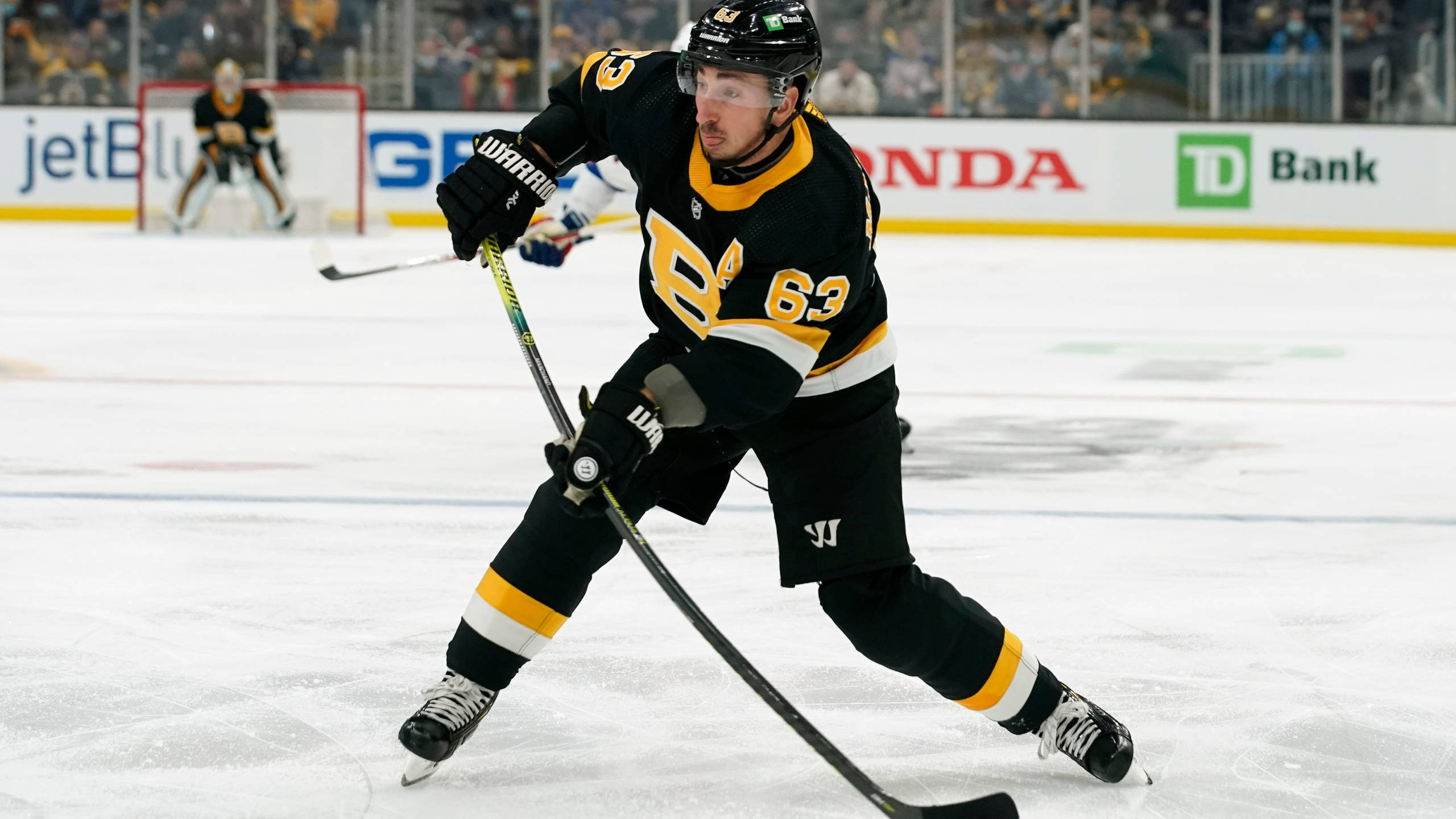布萊德·馬奇安德 NHL 照片 壁紙 — 一名身穿黑色和金色球衣的冰球運動員在比賽中專注於控球，在冰上激烈滑行。