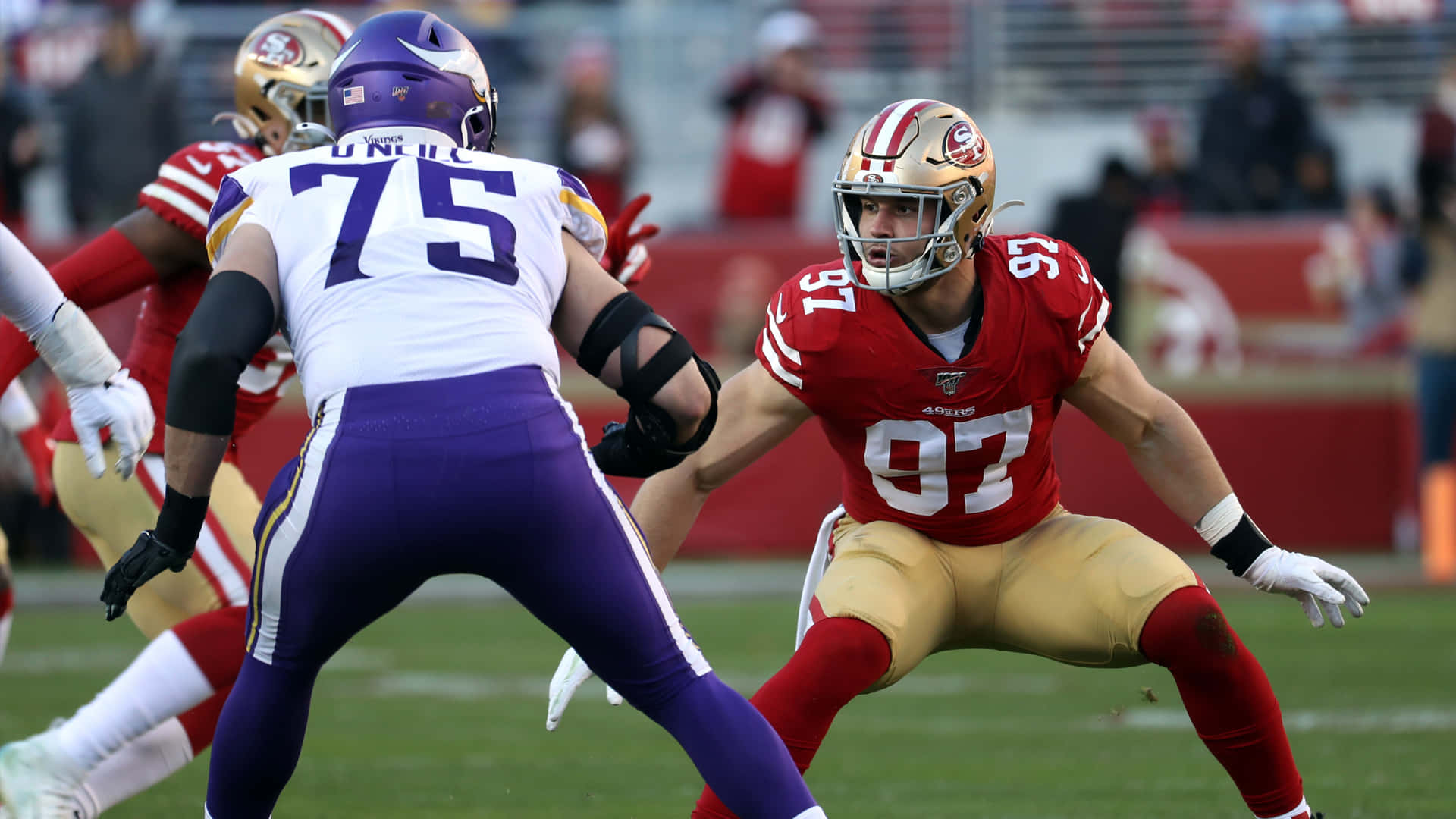 身穿紅金和紫色球衣的NFL足球運動員在綠色場地上競爭。