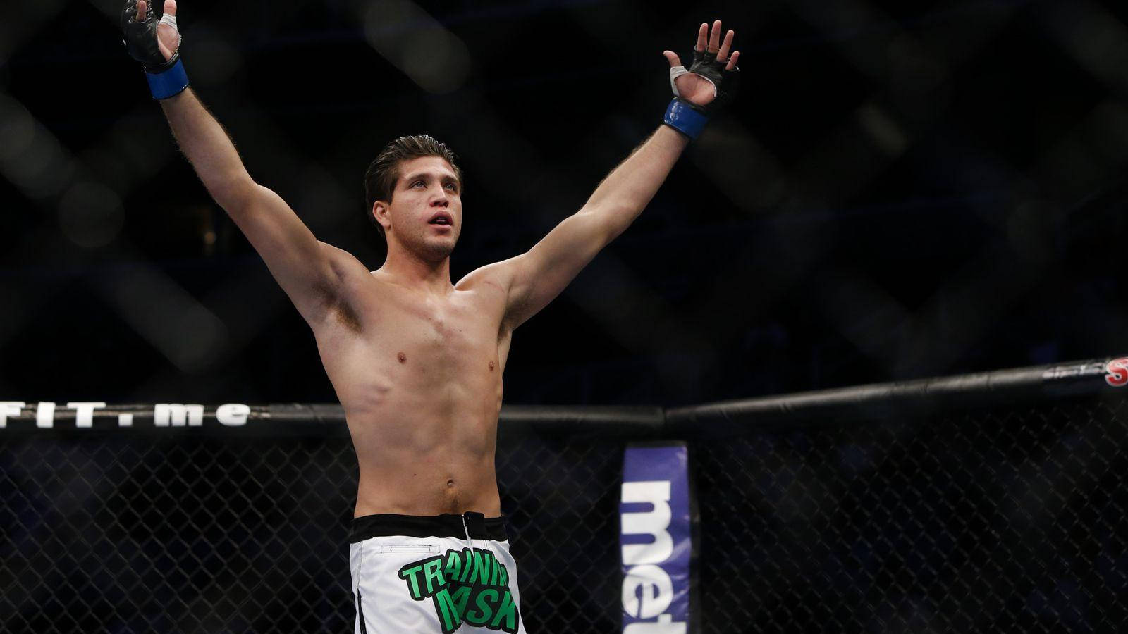 MMA拳手在八角籠中高舉雙臂慶祝勝利。