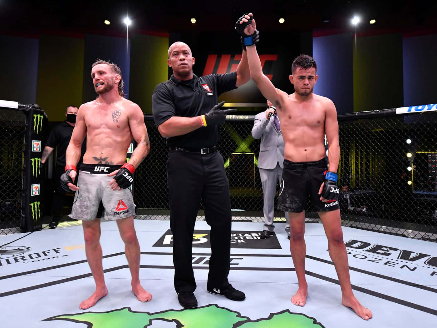 UFC拳手在比賽中獲勝，裁判在八角籠中舉起他的手。