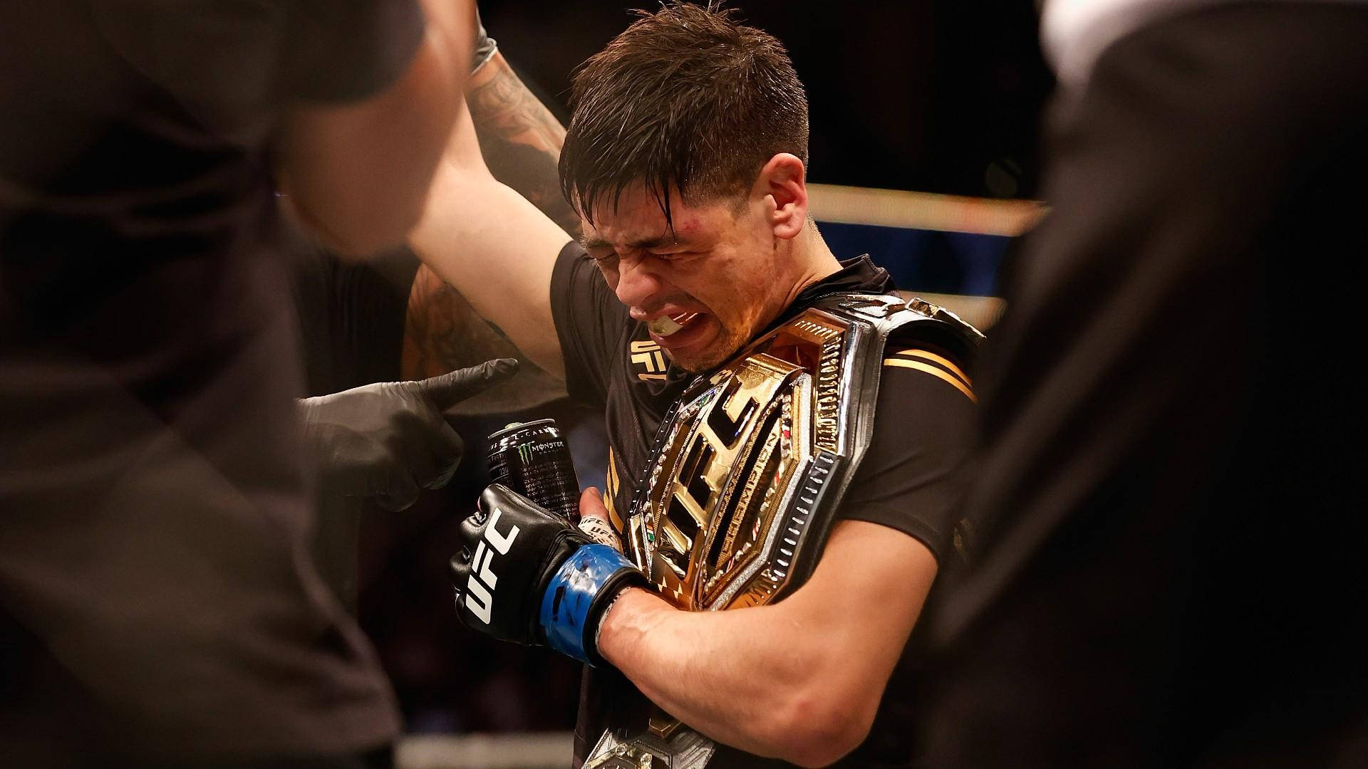 UFC拳手在八角籠中拿著冠軍腰帶慶祝勝利