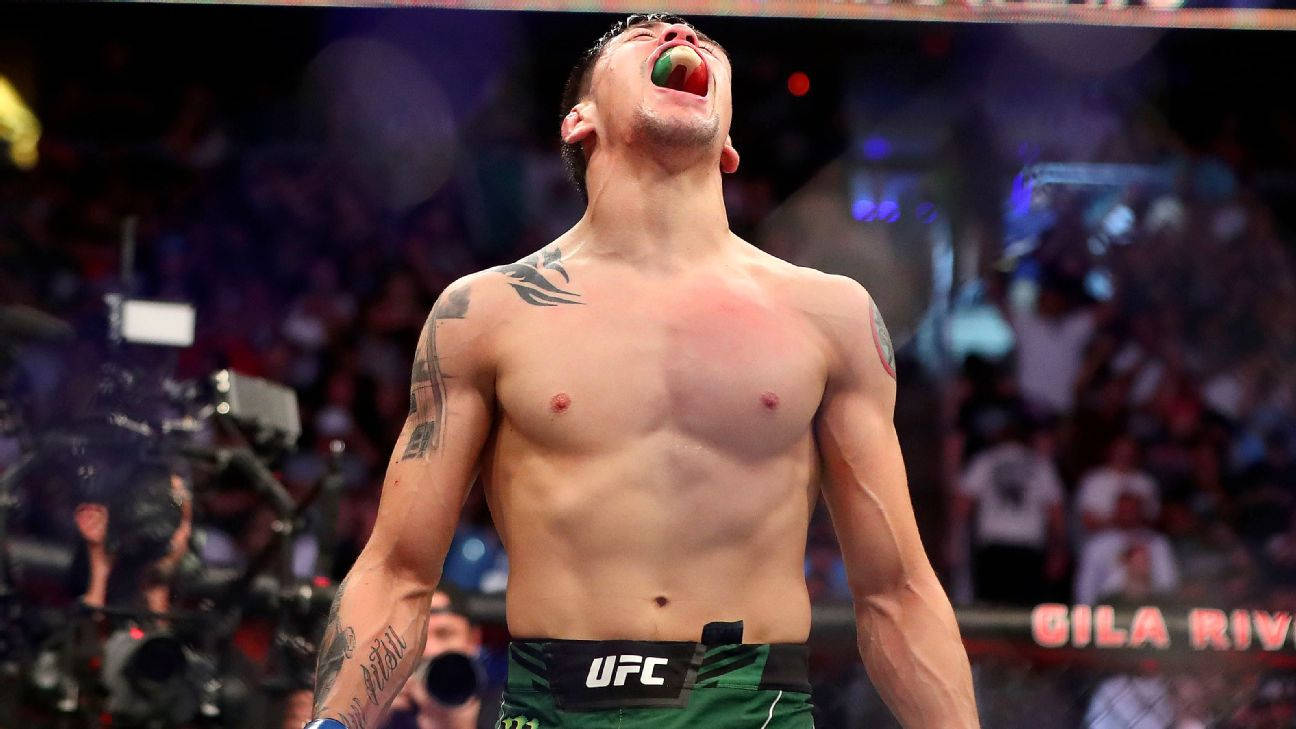 UFC拳手在八角籠中展示牙套和紋身慶祝勝利。