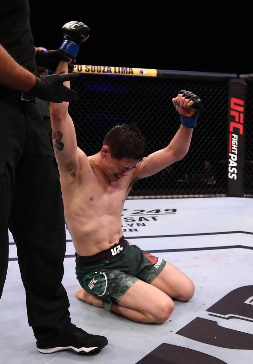 UFC拳手在八角籠中慶祝勝利，裁判舉起他的手。