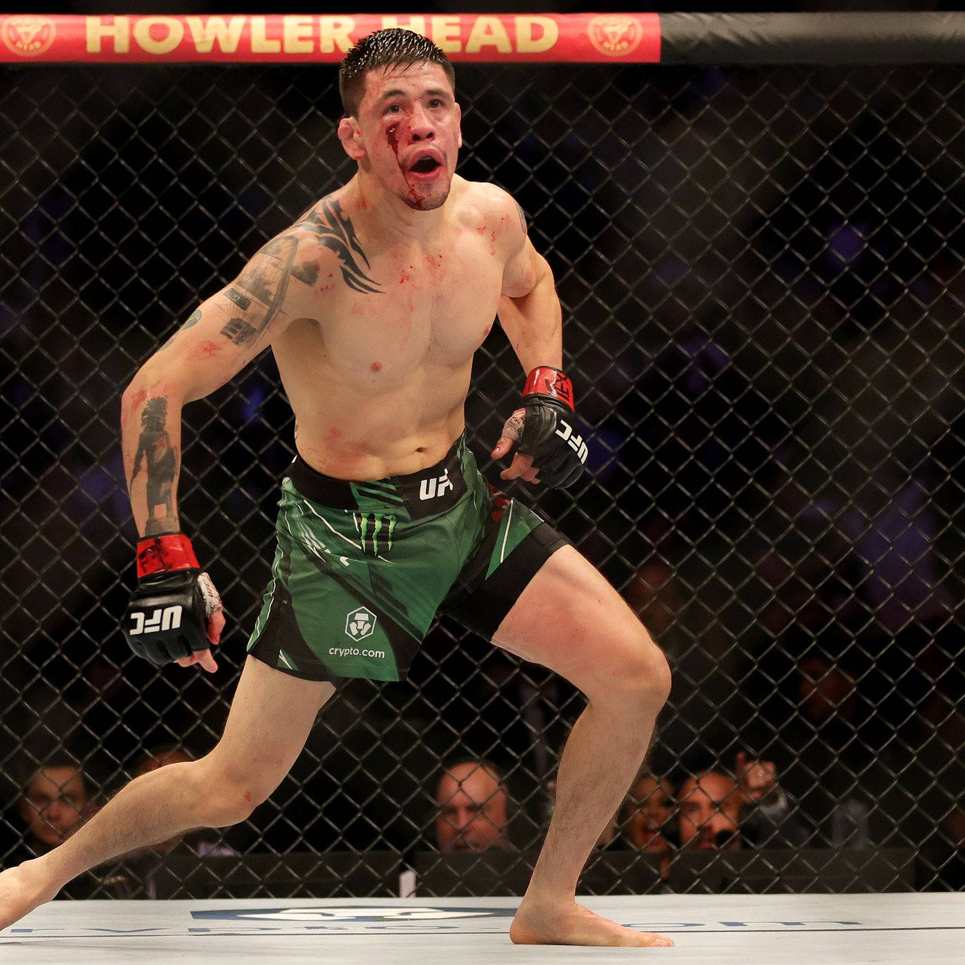 一名血跡斑斑的MMA拳手在八角籠內慶祝勝利。