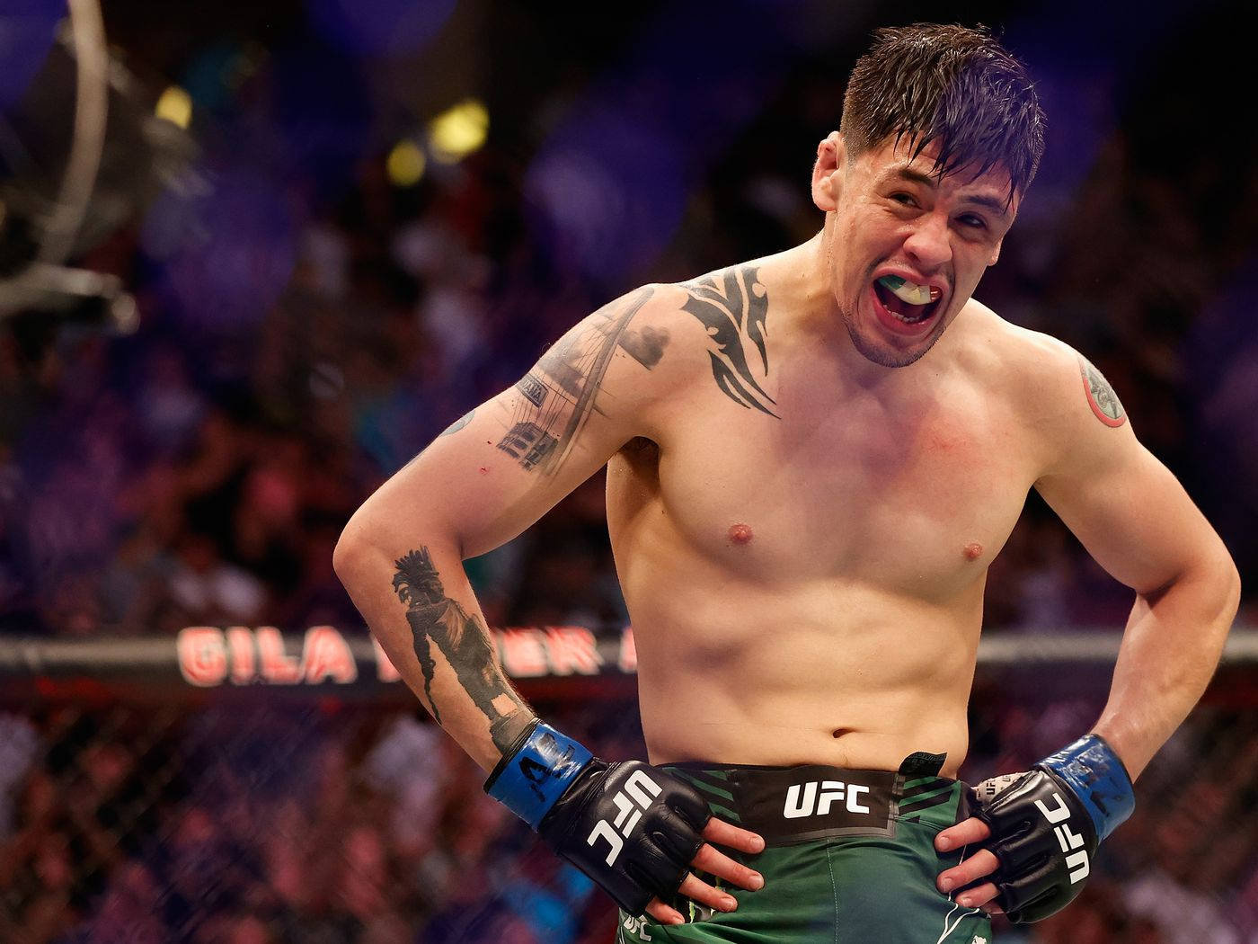 UFC拳手在八角籠中與背景人群慶祝勝利。