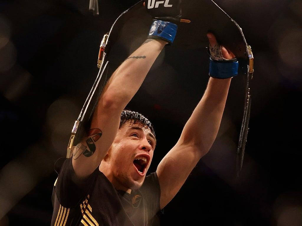 UFC拳手高舉冠軍腰帶慶祝勝利。