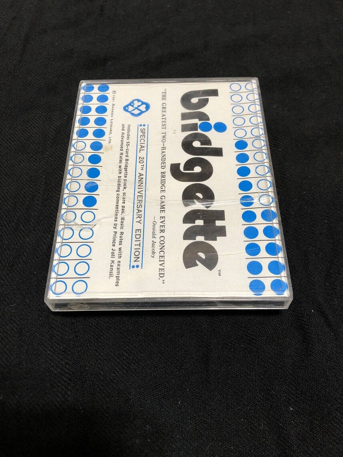 一個帶有藍色圓形的復古Bridgette紙牌遊戲盒，背景為黑色布料。