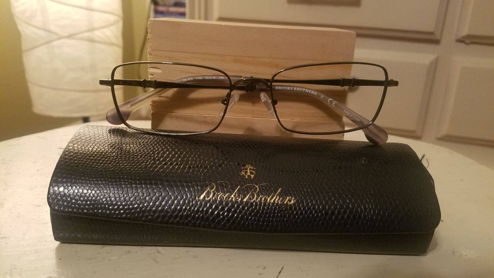 布魯克斯兄弟眼鏡配鏡盒 壁紙 — 一副黑色鏡框的Brooks Brothers眼鏡放在其紋理黑色眼鏡盒上，置於白色桌子上。
