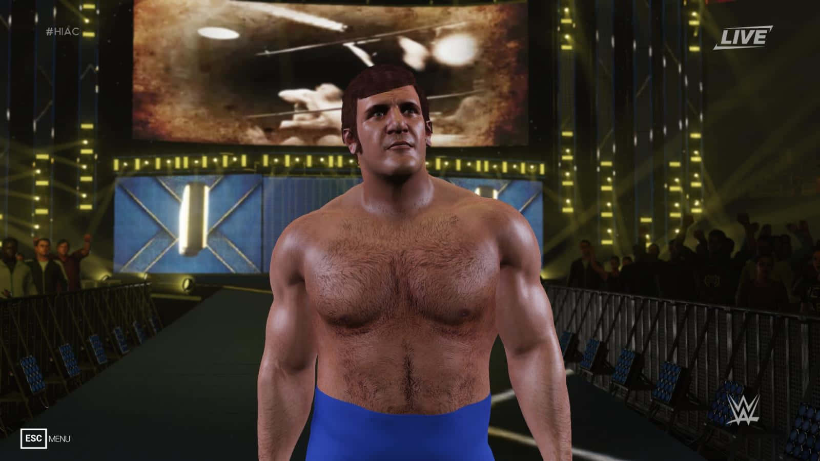 布魯諾·薩馬蒂諾WWE 2K14遊戲角色 壁紙 — 一位肌肉發達的摔角手穿著藍色短褲，在明亮的競技場燈光下站在舞台中央，身後有歡呼的人群。