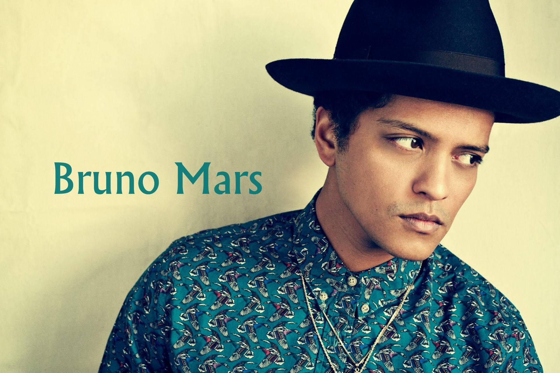 Bruno Mars 戴著黑色軟呢帽和圖案青色襯衫，他的名字以青色文字顯示。