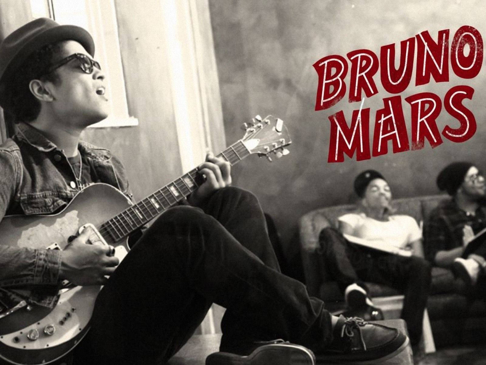 Bruno Mars 與樂隊成員在輕鬆的室內環境中彈奏結他。