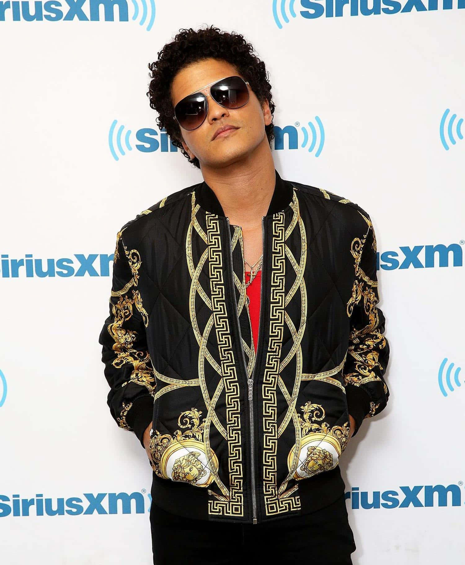 身穿金色圖案飛行員夾克的男子在SiriusXM活動中擺姿勢。