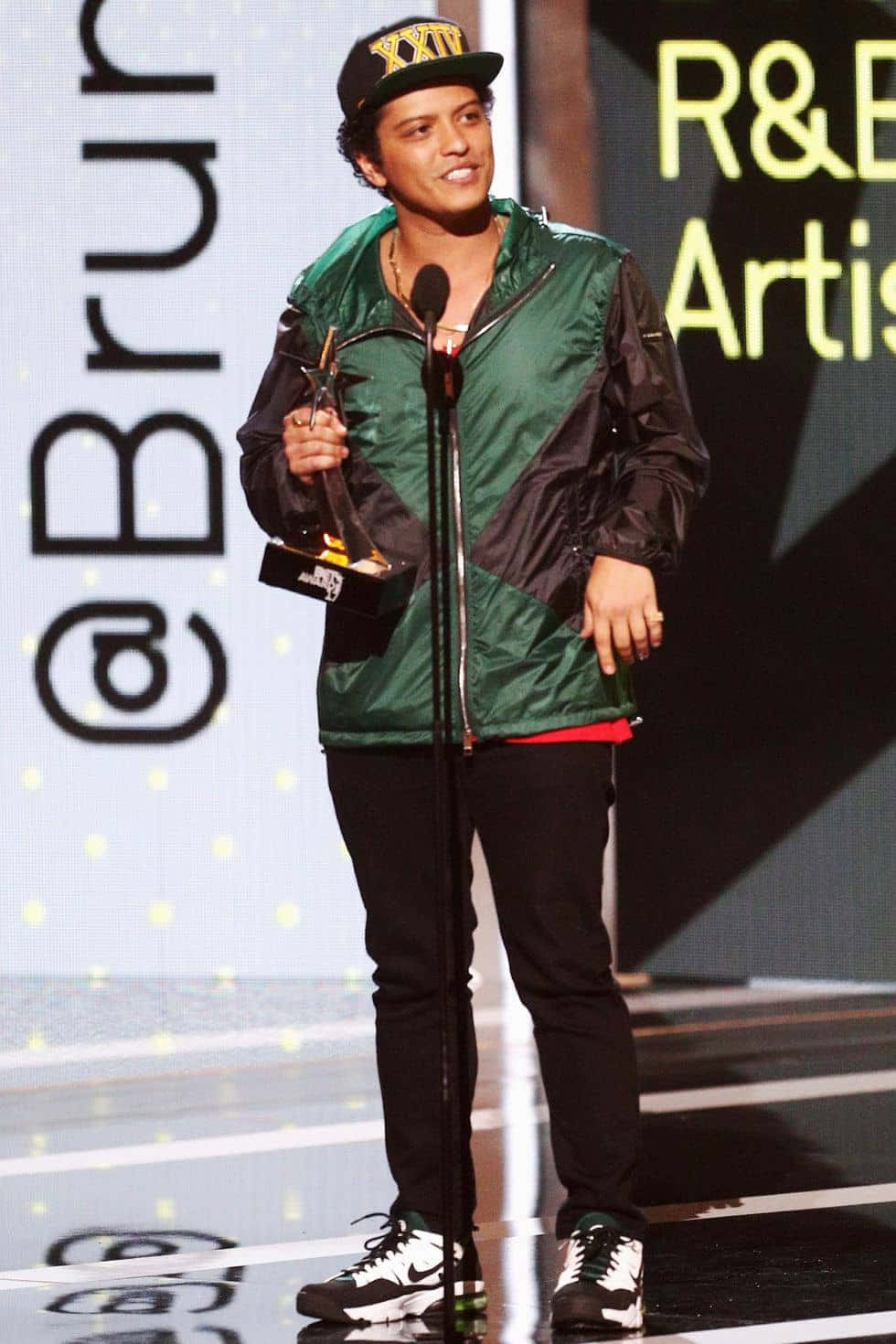 Bruno Mars 在R&B藝術家活動的舞台上手持獎項。