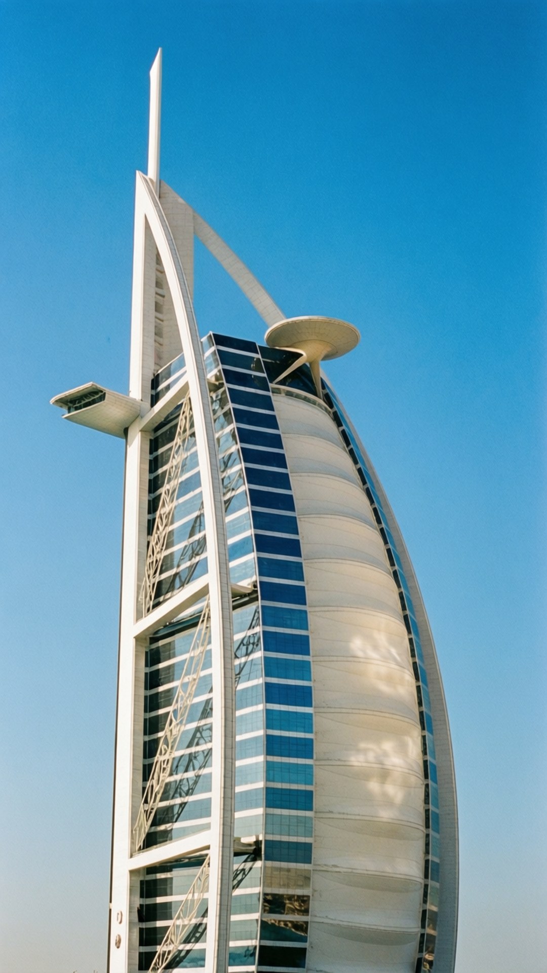 帆影藍天 壁紙 — 帆船造型的帆船酒店 Burj Al Arab Jumeirah 在清澈的藍天下，以銳利的建築線條和反光玻璃高聳入雲。