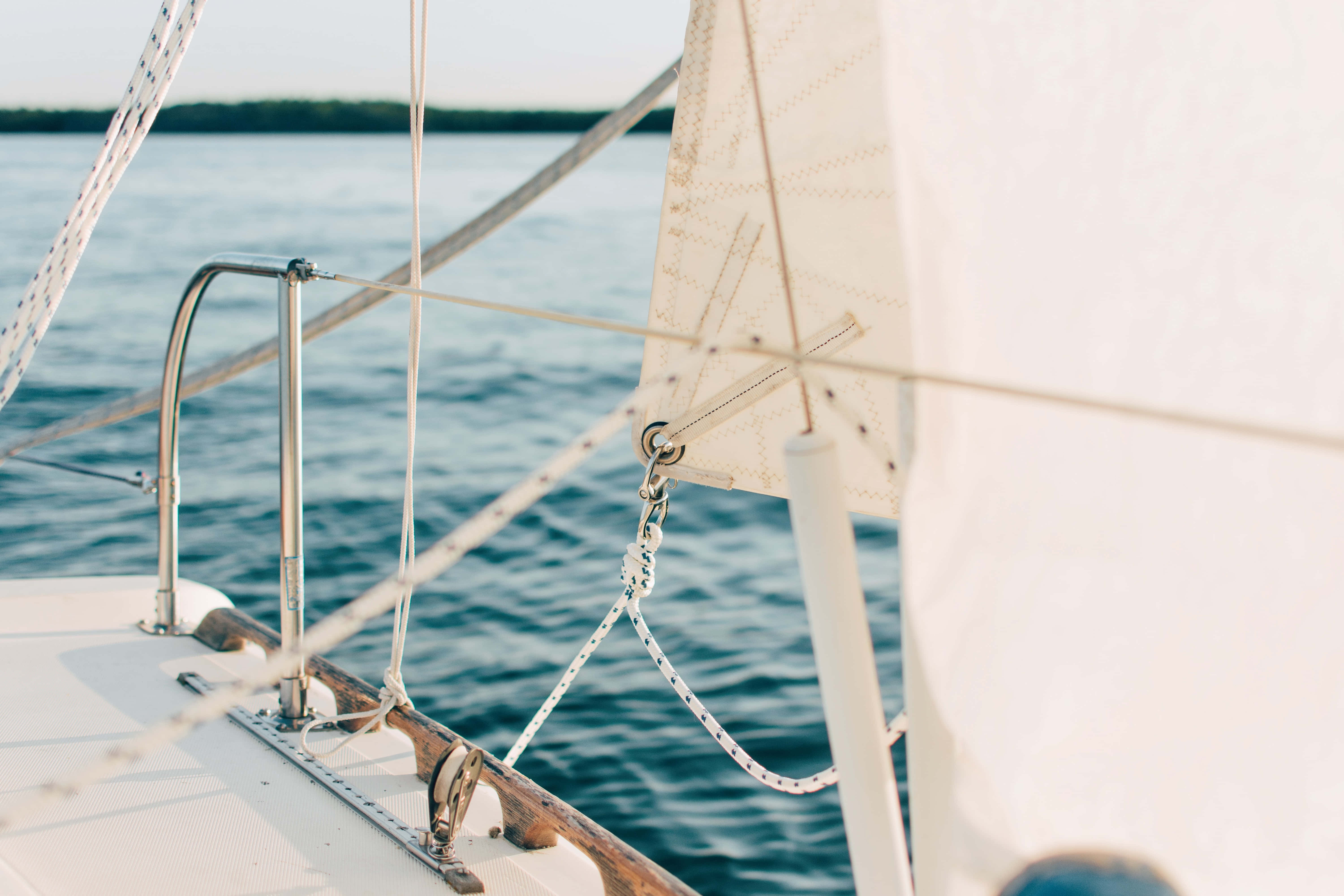 Boating 桌布 壁紙 — 帆船甲板同白色帆布喺平靜藍色海水同柔和日光下嘅特寫。