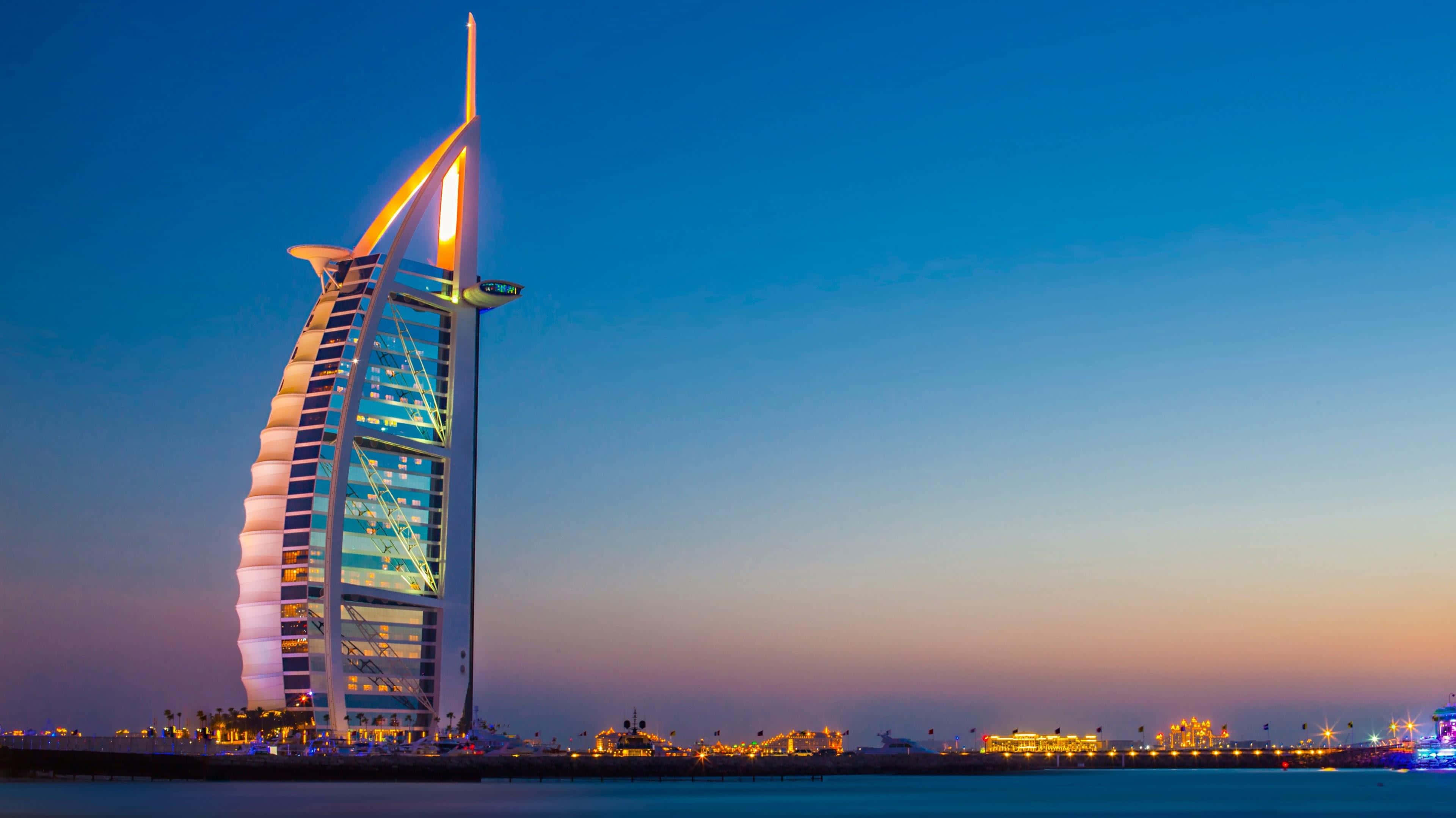 Dubai 桌布 壁紙 — 帆船酒店在杜拜海濱的暮色天空下散發著溫暖的光芒。