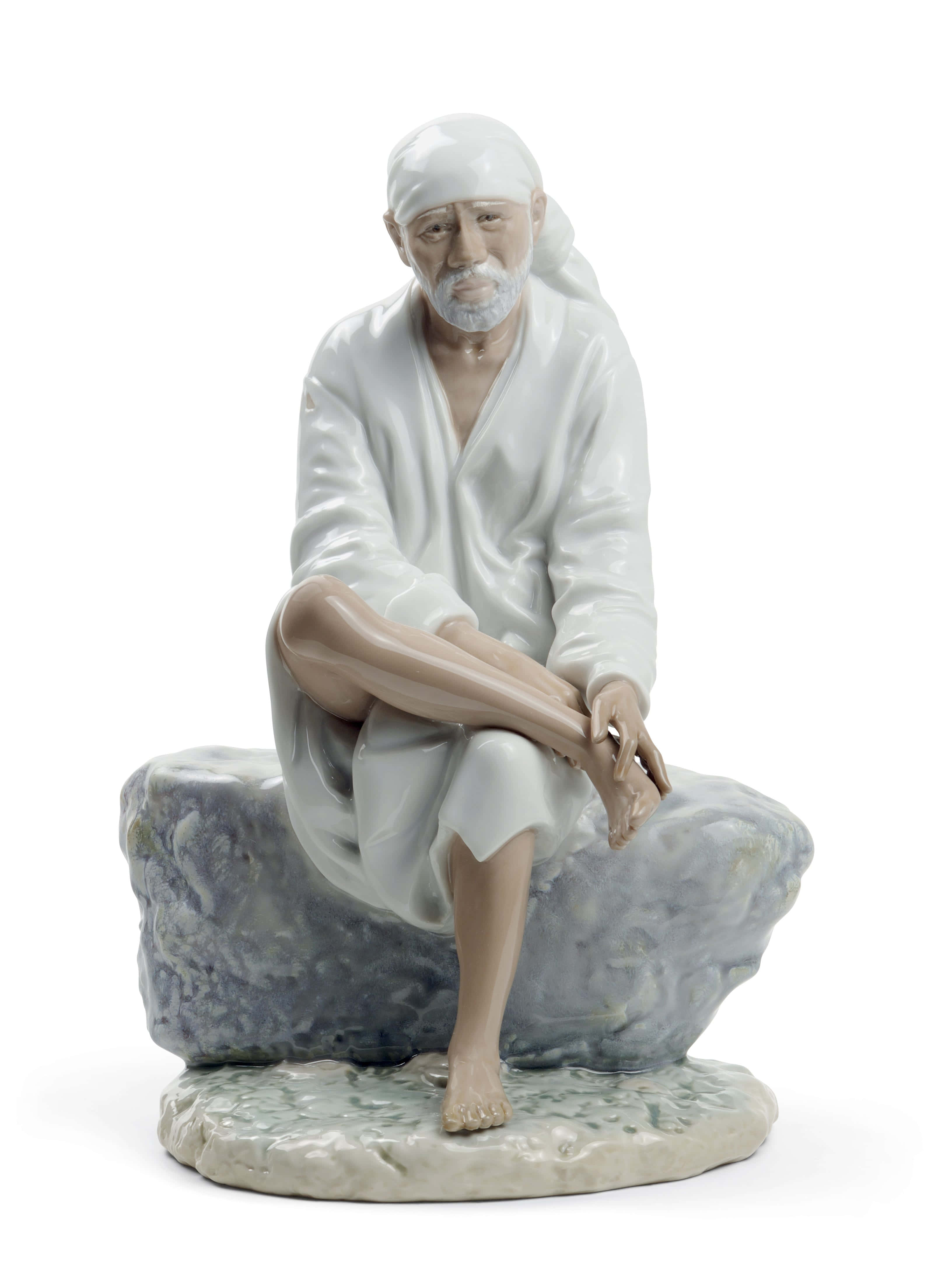 希迪 Sai Baba 人偶畫像 壁紙 — 一個寧靜的瓷器公仔，描繪一位留著白鬍子、戴頭巾的長者，沉思地坐在一塊有紋理的灰色岩石上。