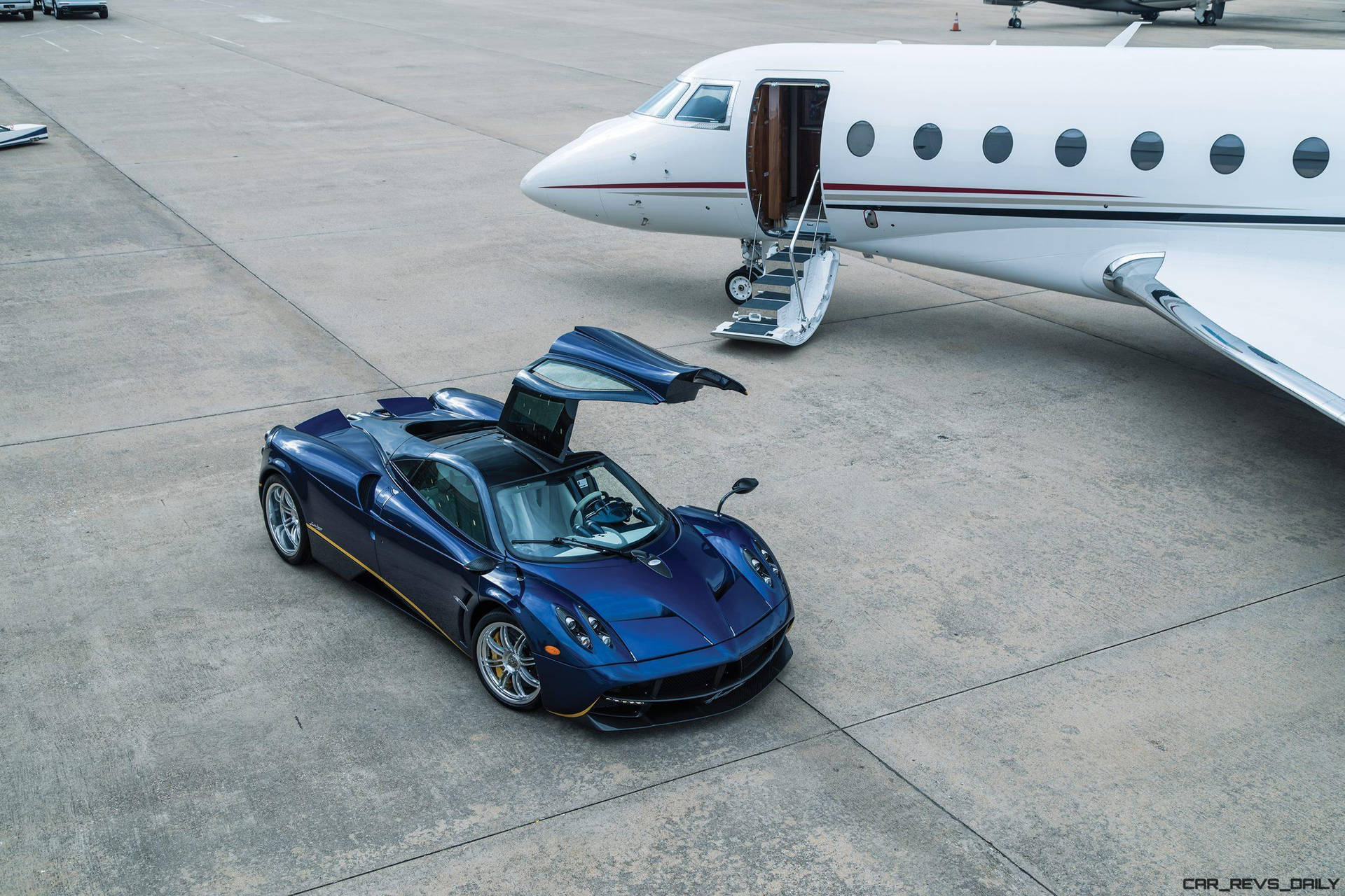 藍色Pagani Huayra跑車停在停機坪上私人飛機旁邊。