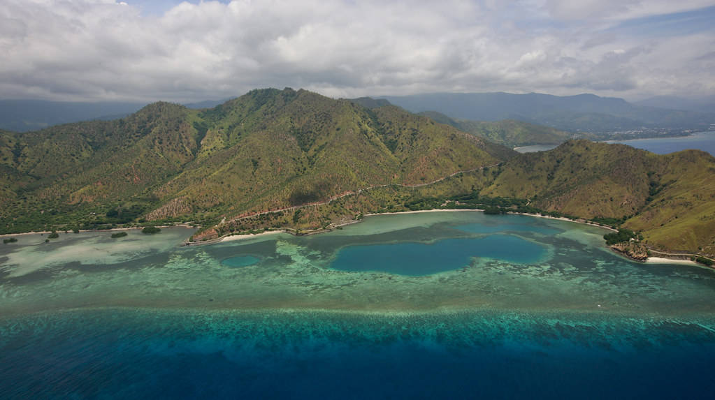熱帶島嶼海灣，碧綠海水與青山在陰天之下。